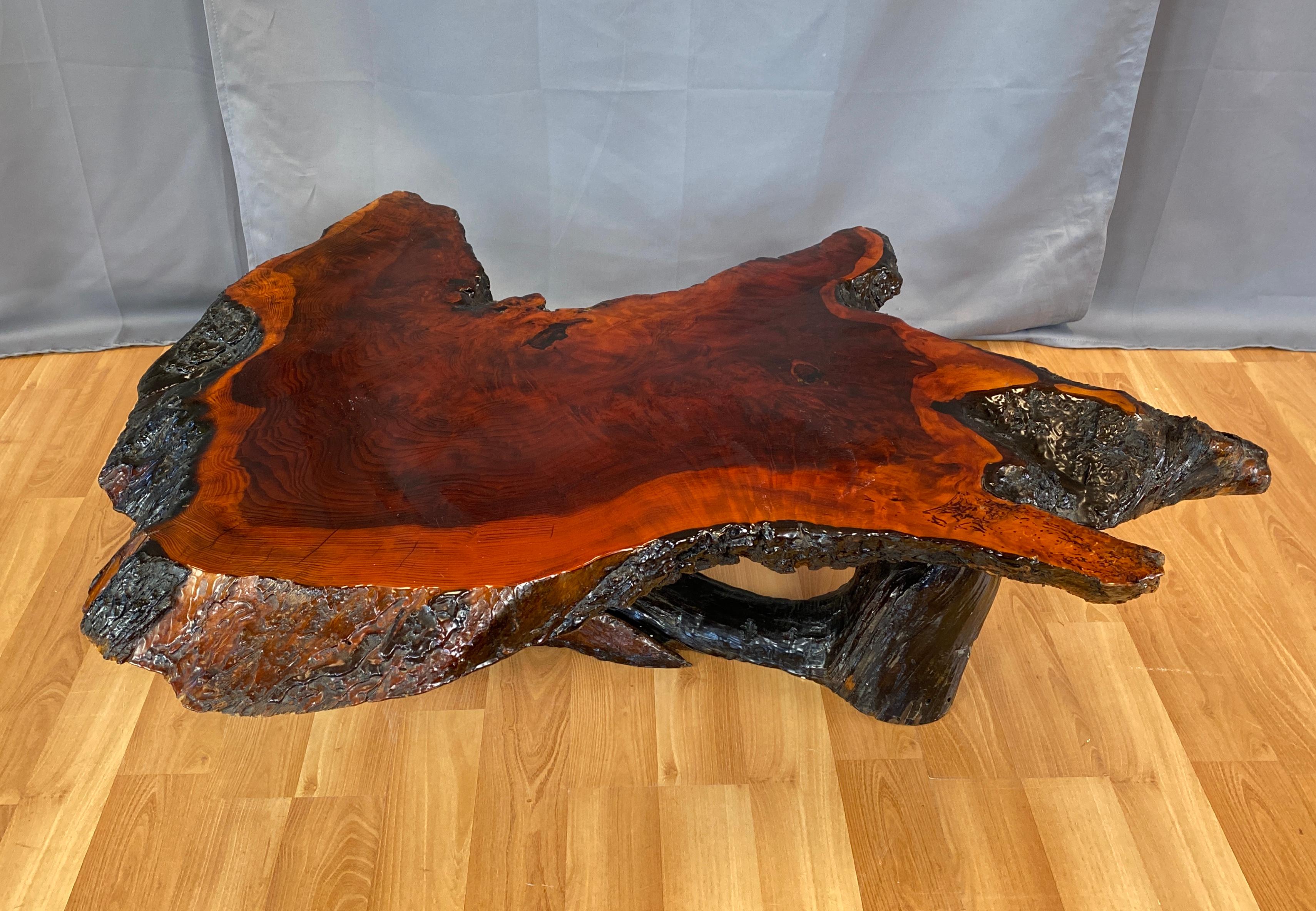 Live edge redwood slab coffee table or end table

A substantial 1970s live edge redwood slab coffee table on a large root base. Impressive richly toned old growth redwood with charred bark edges and darkened internal tree rings.
Finished in a