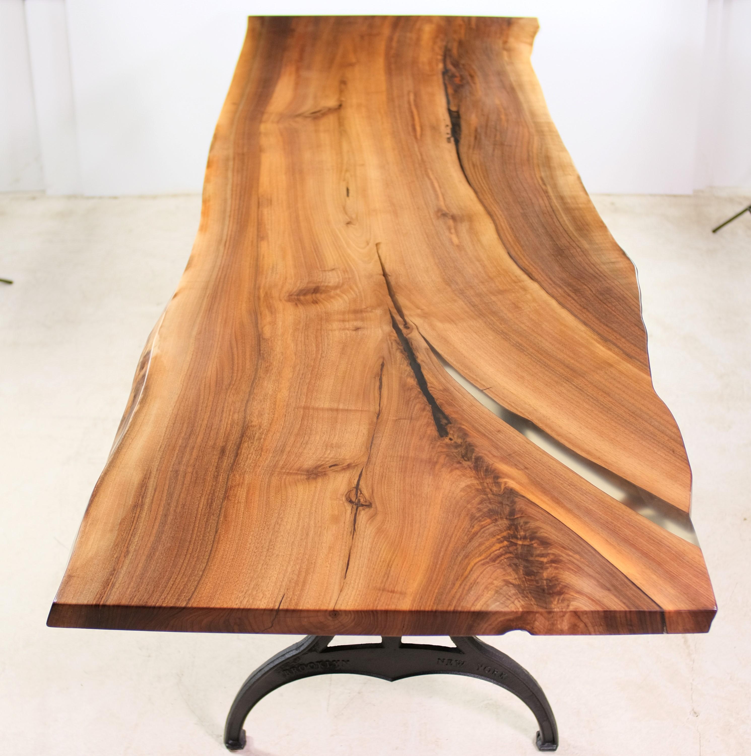 Made from a single slab, this live edge walnut table features a natural open accent filled with clear resin. Mated with industrial cast iron legs that say Brooklyn, New York in raised lettering. This can be seen at our 400 Gilligan St location in