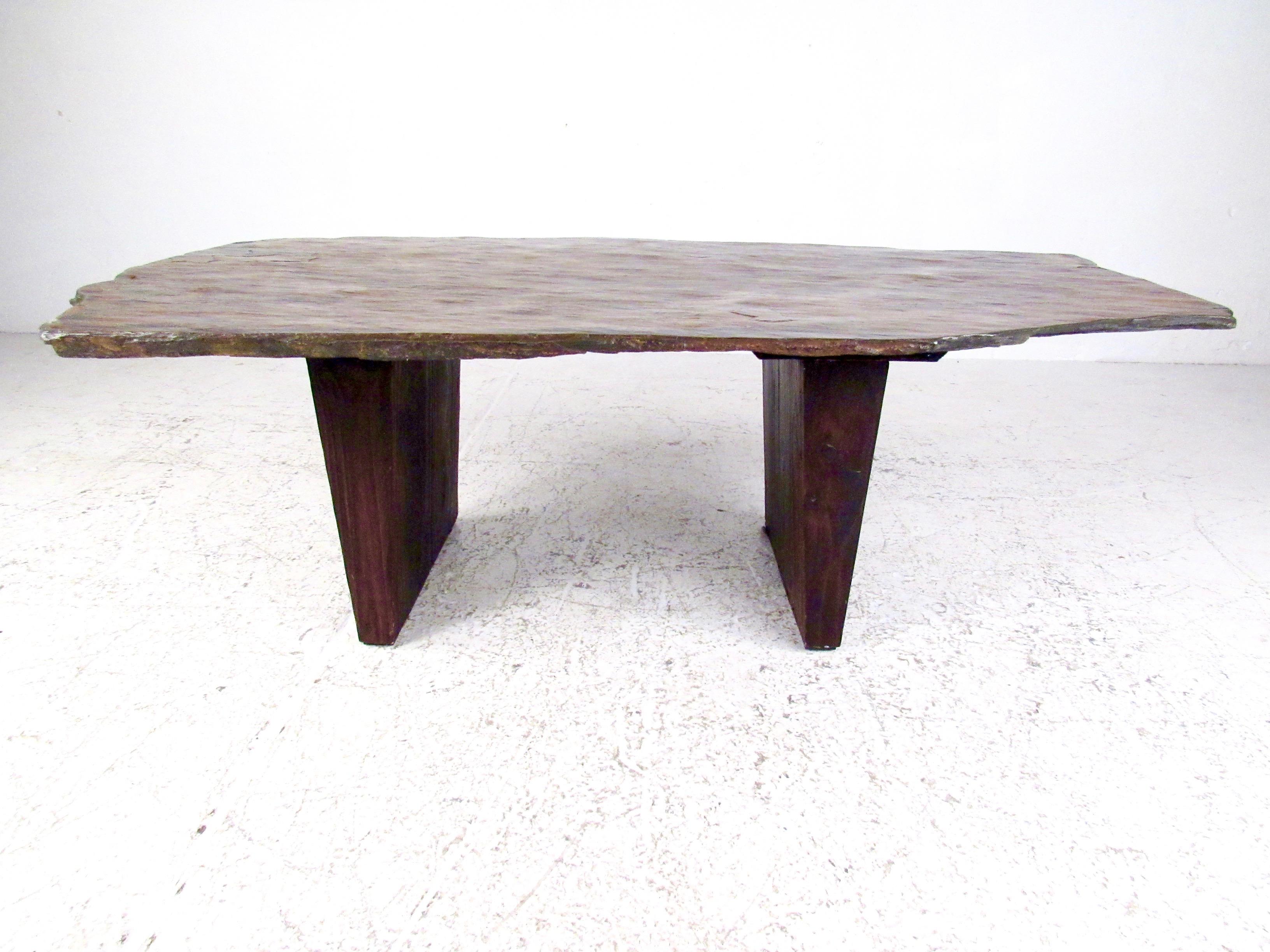 This impressive studio made coffee table features hardwood slab legs and a striking natural finish slate top. The natural beauty of the live edge slate top is complimented by the unique coloring of the stone. Memorable and substantial vintage coffee