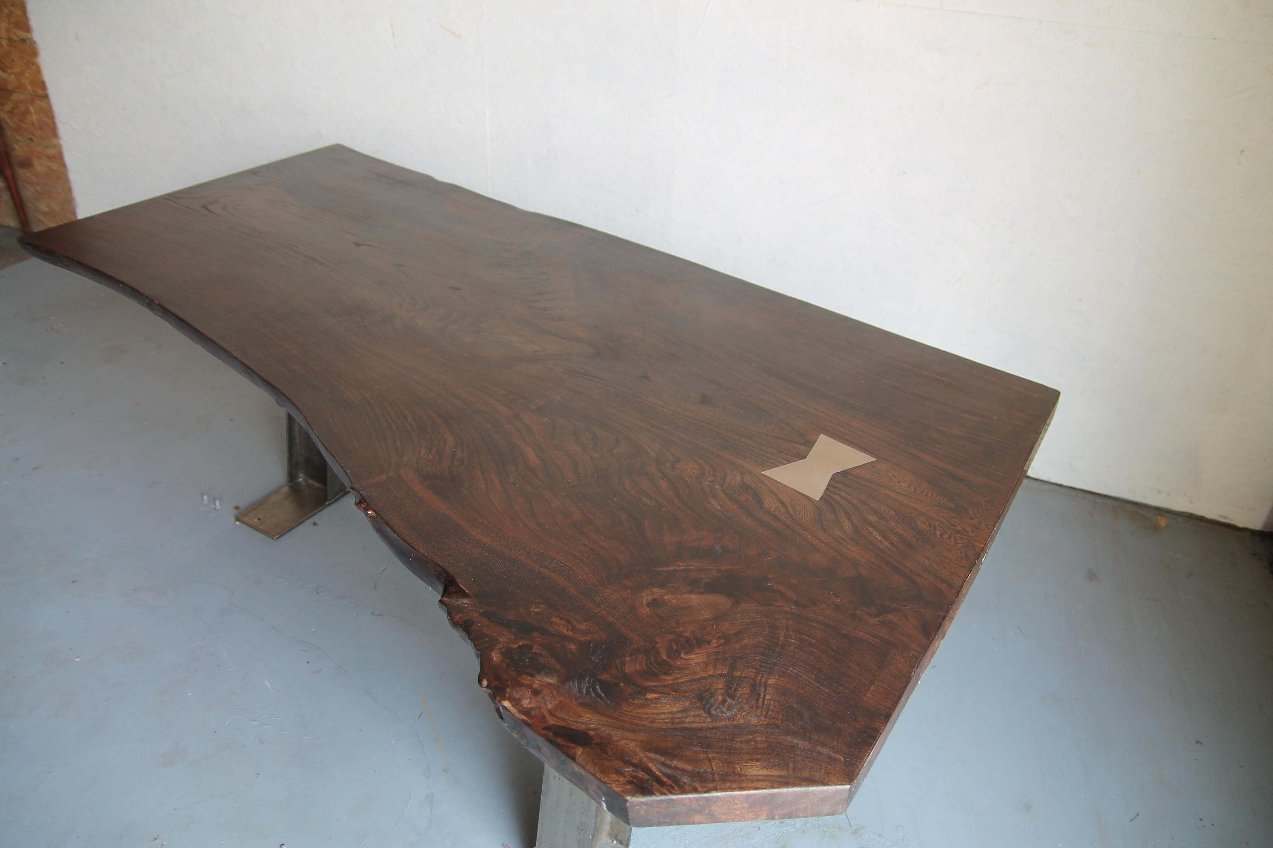 We are pleased to offer this wonderful 7 foot live edge table with custom 3-leg metal base. Wood is English elm stained with walnut stain and had a great large brass butterfly on top. Would make a great small dining table or desk.