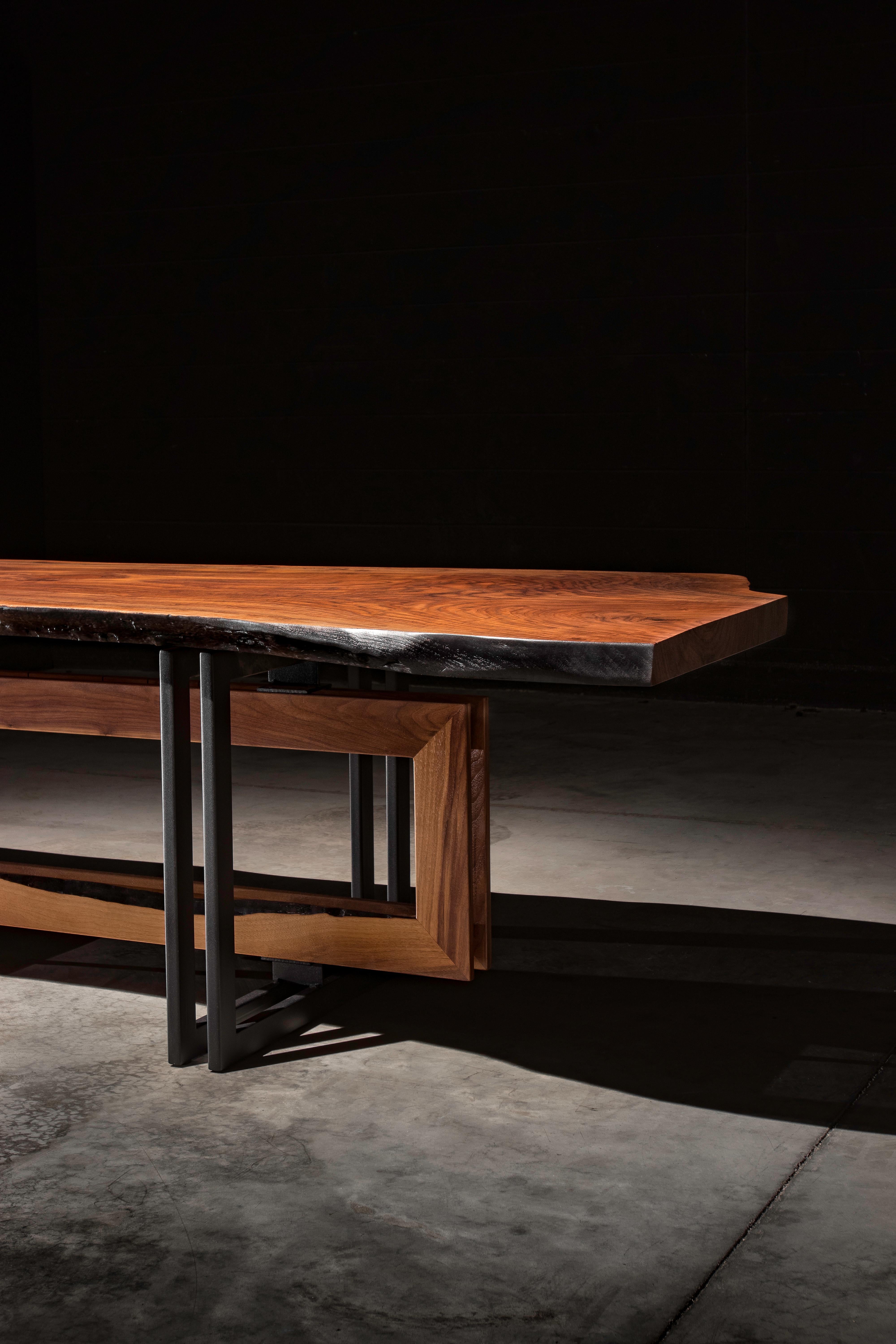 The alter dining table mixes the natural wood grain of a solid a walnut slab and the modern geometric elements of a blackened steel and walnut base to form an item that will make a statement to any dining room.

This is a made to order item