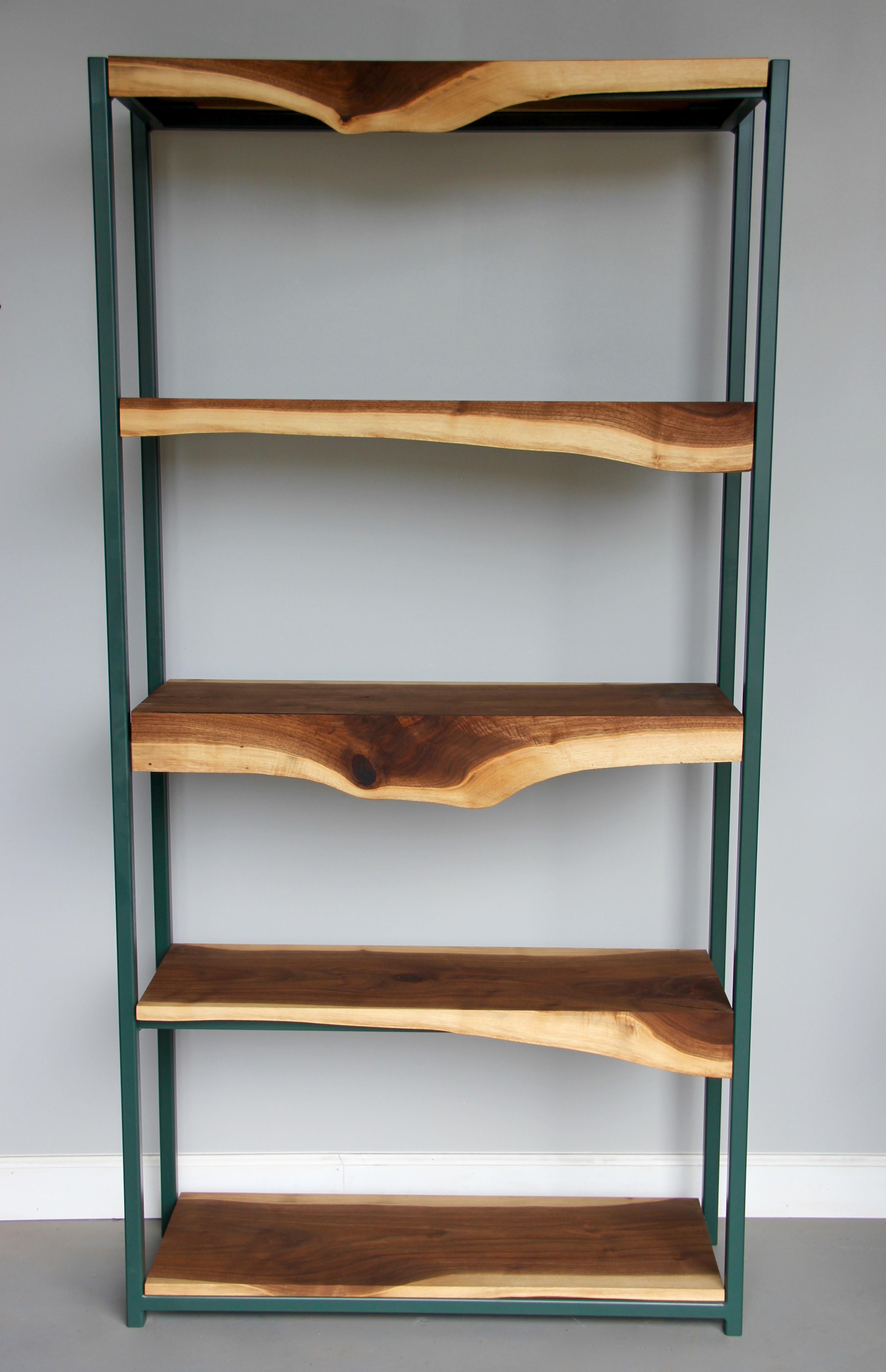 This sleek live edge walnut and steel bookshelf is made by hand in our workshop near Detroit, Michigan. It has a sturdy welded steel frame finished in a deep forest green color, and is paired with handmade walnut live edge slab shelves. One of a