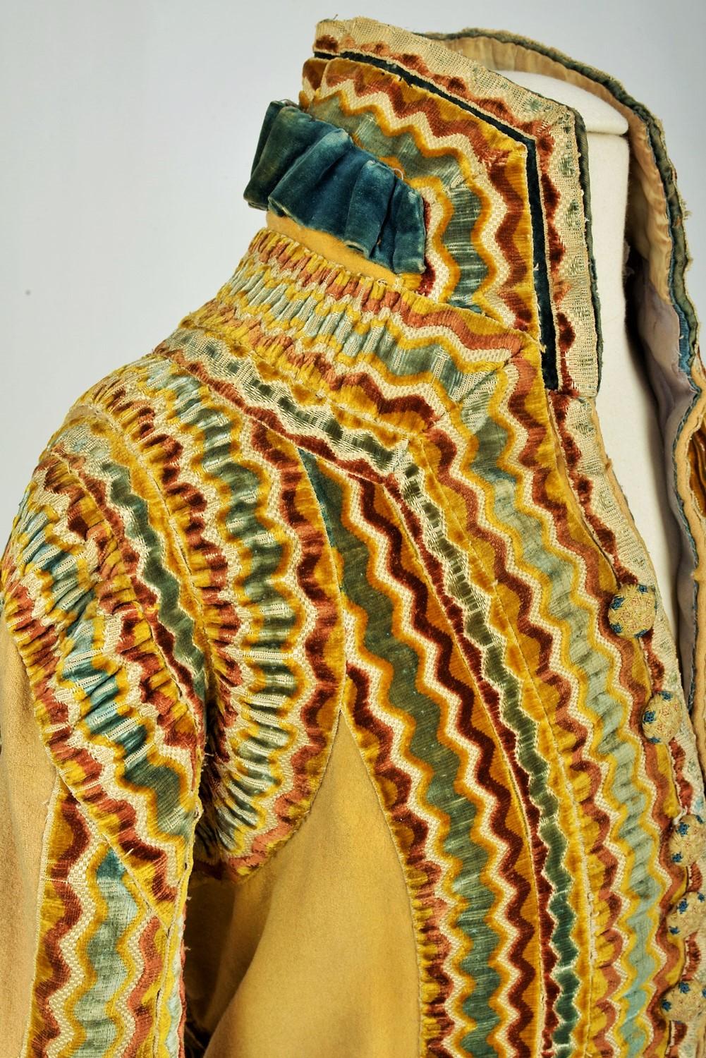 Circa 1800-1830
England

Spectacular British livery in straw yellow woolen cloth applied with velvet ribbons dating from the early 19th century. Fitted frock coat with a high raised collar, long angled sleeves, slit in the back basques. Work of