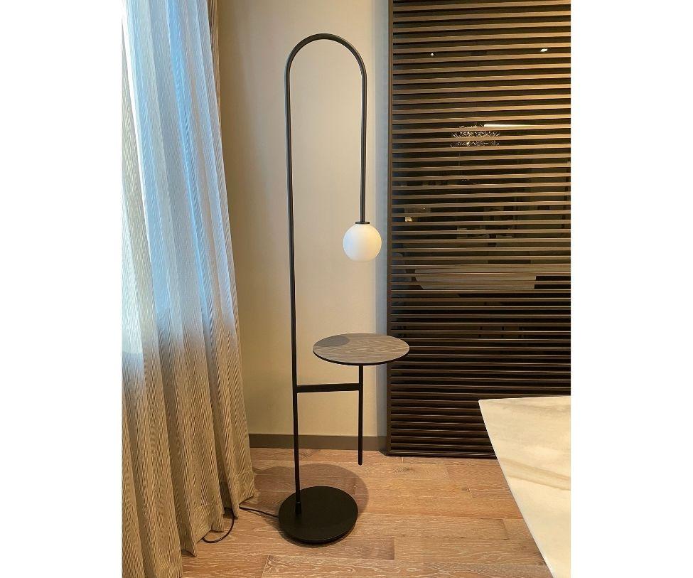 Designed By Keiji Takeuchi 

Its slender and graphic silhouette, with retro style references, is the result of a skilful construction: a base to provide stability, a metal tube that curves and ends in a source of light and a table connected to it;