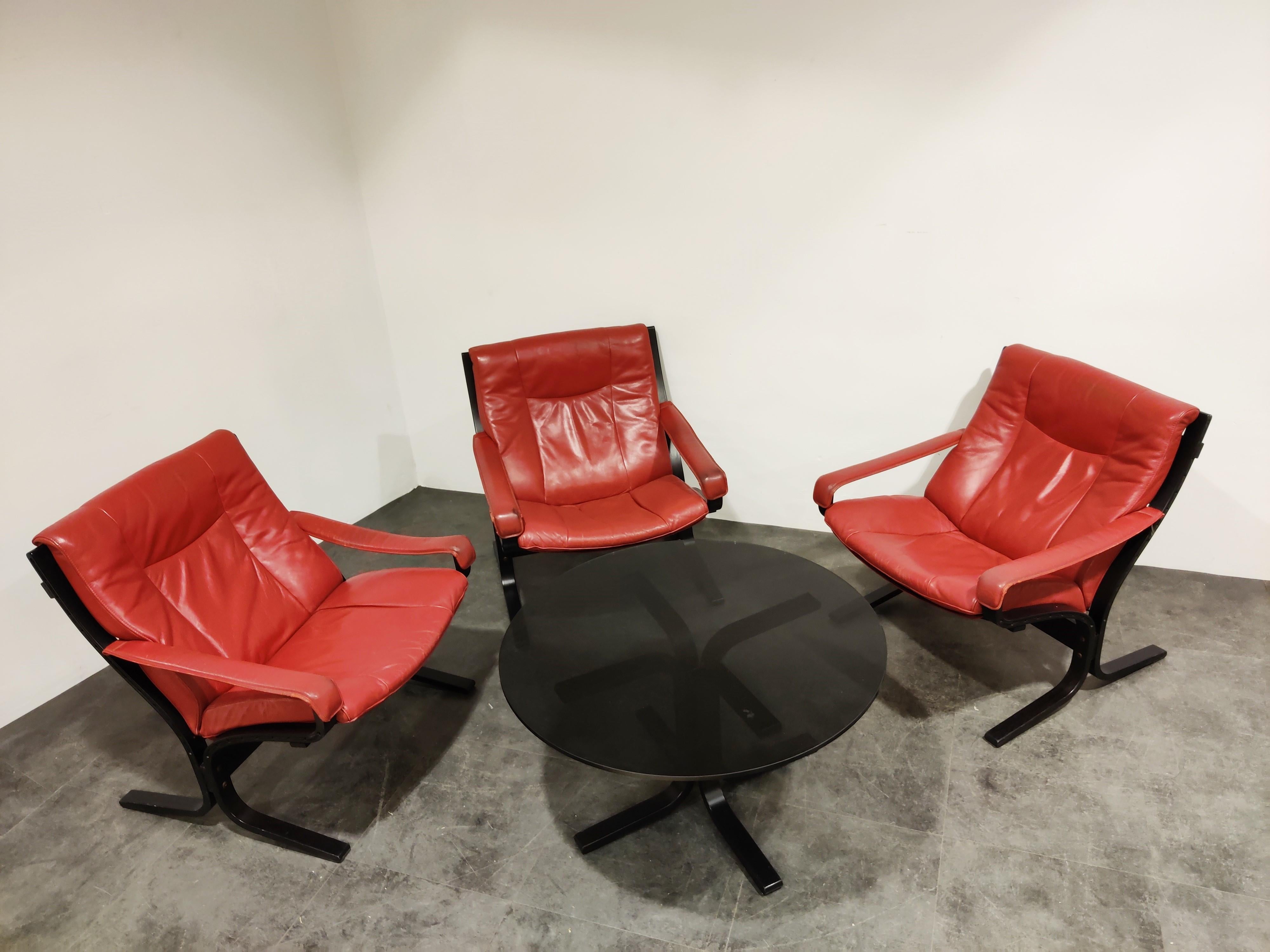 Rare vintage living room set designed by Ingmar Relling for Westnofa.

The set consists of 3 'siesta' armchairs and a matching coffee table.

The armchairs have an original and rare red leather upholstery on a black wooden frame.

The coffee