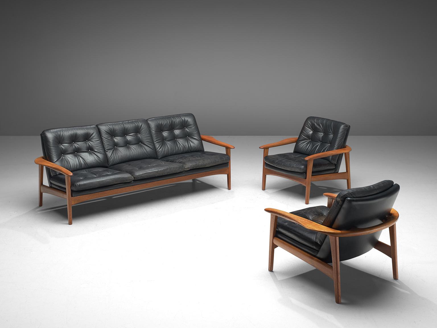 Pair of easy chairs and settee, black leather and teak, Denmark, 1960s.

This set of easy chairs and sofa feature a teak frame with a tufted seat and back. The chairs have a sturdy frame showing refined craftsmanship, holding a comfortable leather