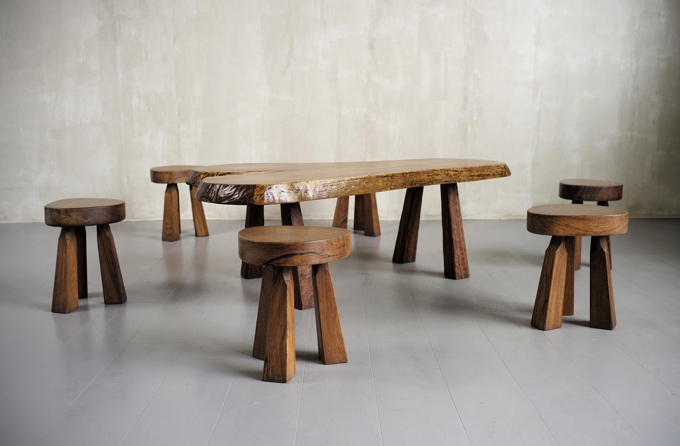 Set composed of a large coffee table and six stools made in Senegal in the 60s. The top of the coffee table (140 cm / 90 cm) is composed of a slice of Vene, resting on four legs. The tripod stools have a triangular seat.
The craftsman-creator of