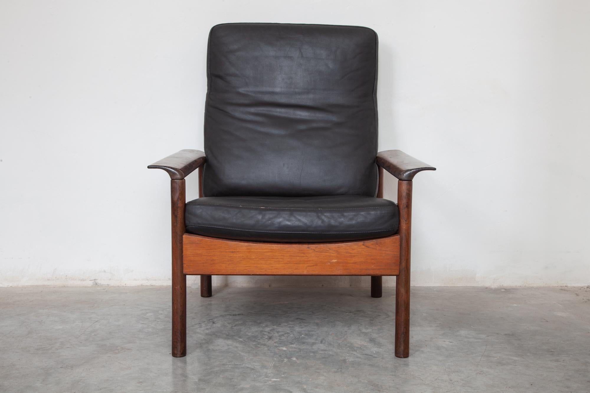 Fifties lounge chair set by Gervan, Belgium. Two high back and two low back chairs. Elegant wood frame with wide sculpted armrests. 
The cushions rest on rubber banding for the seat and tension string for the backrest. Original black leather
