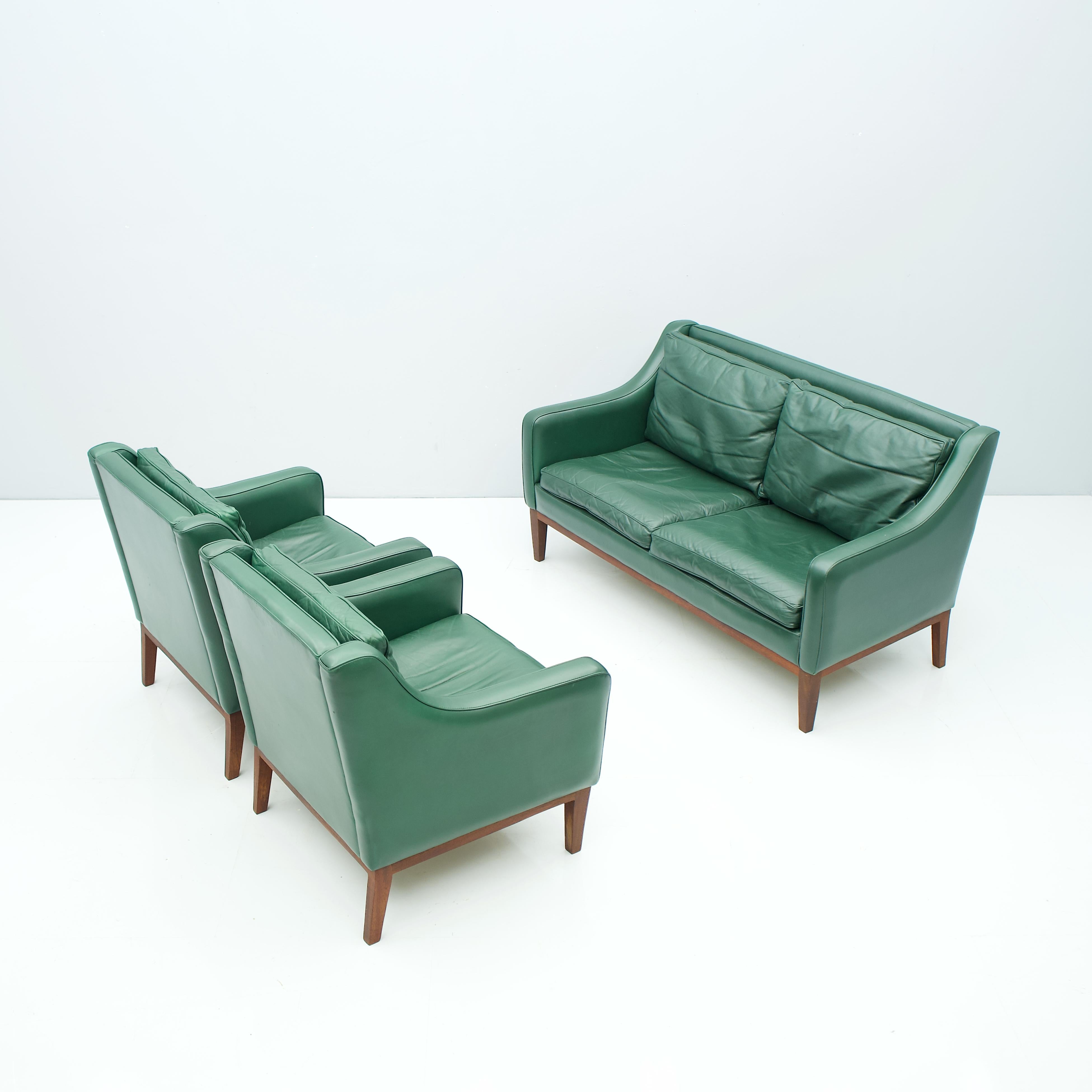 Beautiful living room set in green leather, Italy 1958.
2-seat sofa and two lounge chairs in green leather and wood frame (teak). The pillows are partly filled with down. The Set was bought in 1958. Origin Italy. 
Measures: 
H 76.5 cm, W 137 cm,