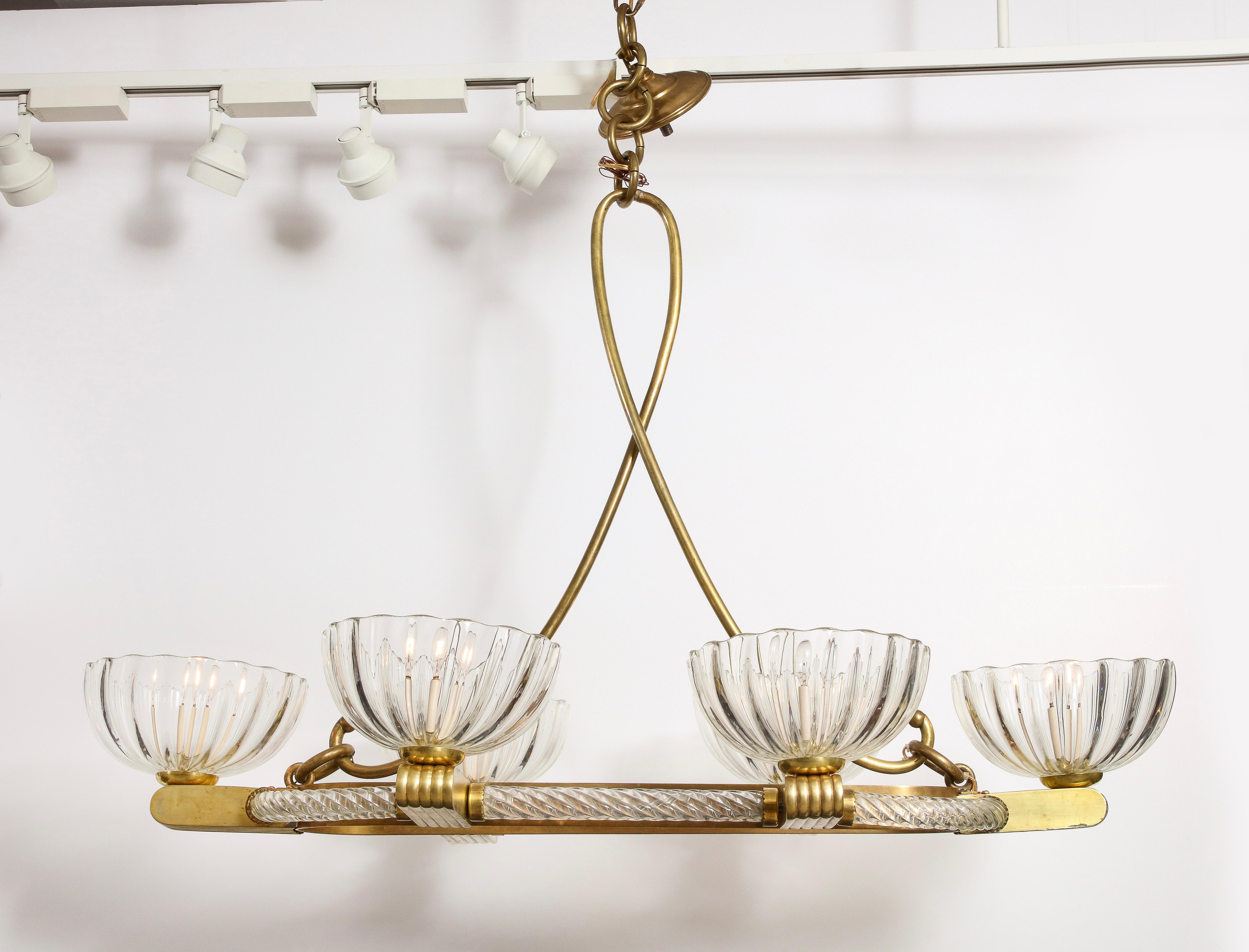 A Livio Seguso mid-century six light Murano oval chandelier, the inner ring comprised of brass, the exterior rimmed with hand blown spiraled glass from which six fluted brass arms terminate in fluted upturned glass bowls suspended by an elegant