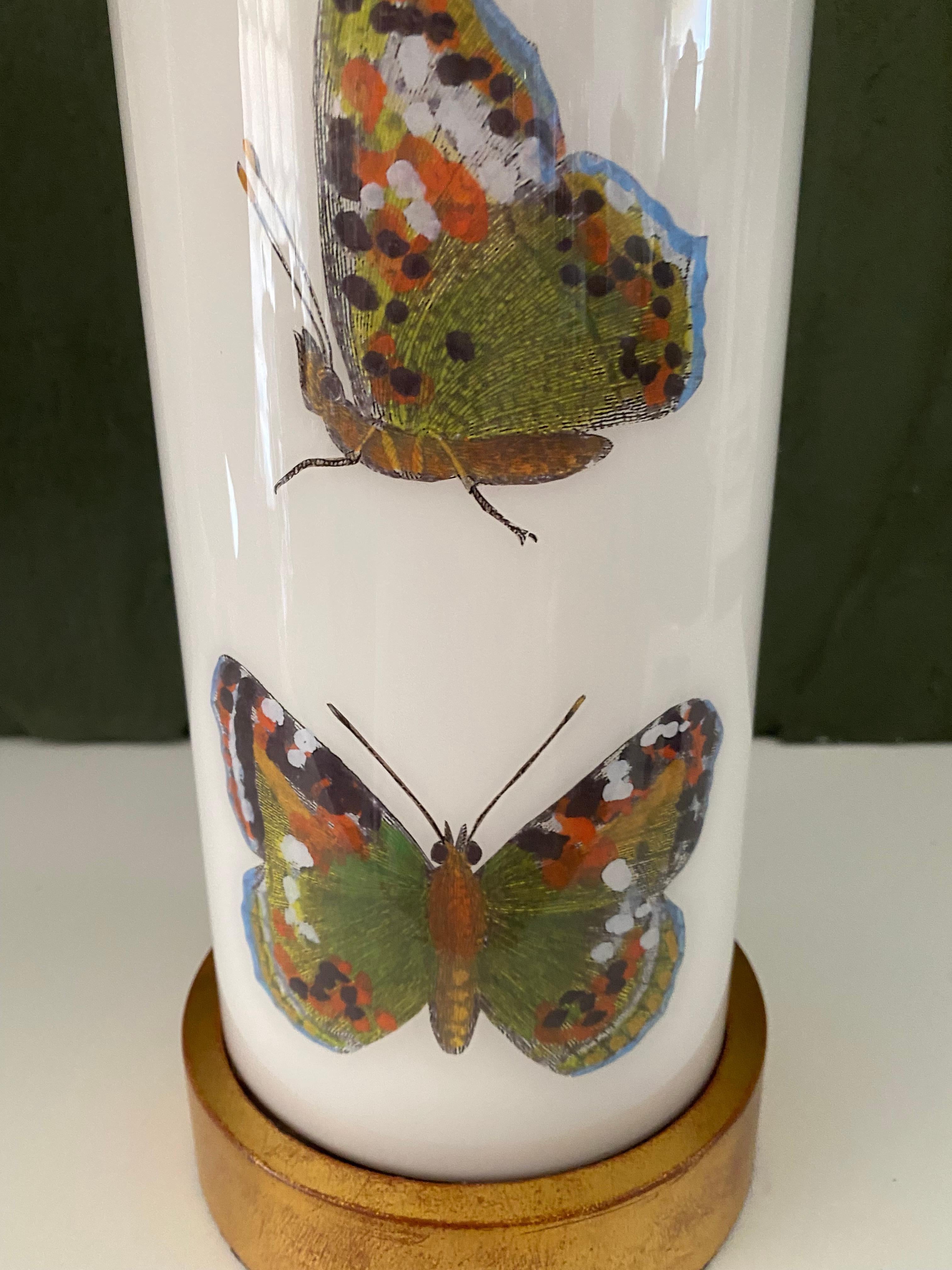 Hand made with care in Houston, Texas. This glass lamp features a selection of 18th century hand-colored engravings of beautiful butterflies in green hues against a soft white background, with hand-turned lightly distressed, gilt wood base and cap