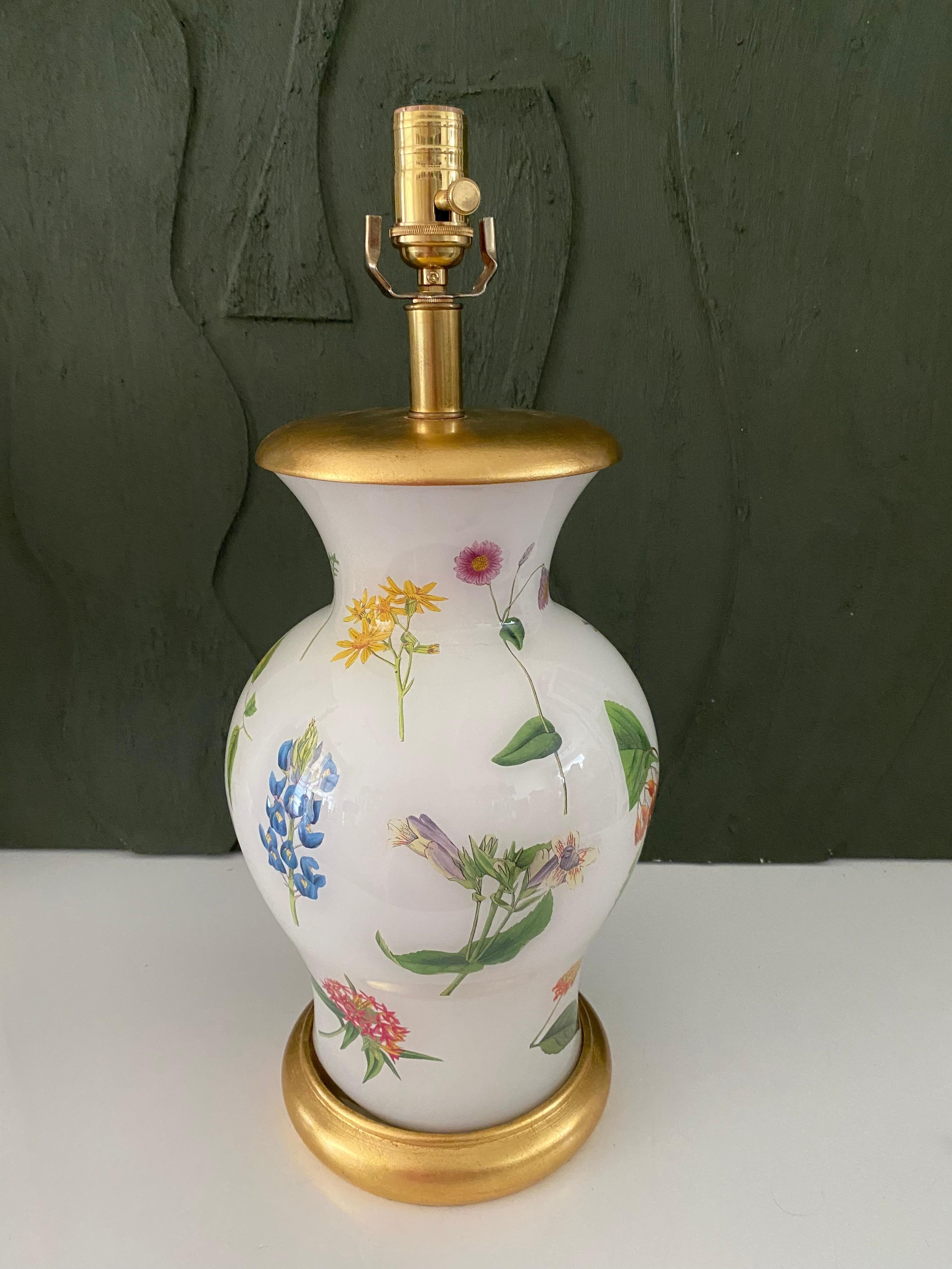 Hand made with care in Houston, Texas. This lamp features a colorful, lively floral pattern that circles the entire piece. Created using an assemblage of 18th century botanical engravings on a soft white ground color with gilt wood base and cap, and