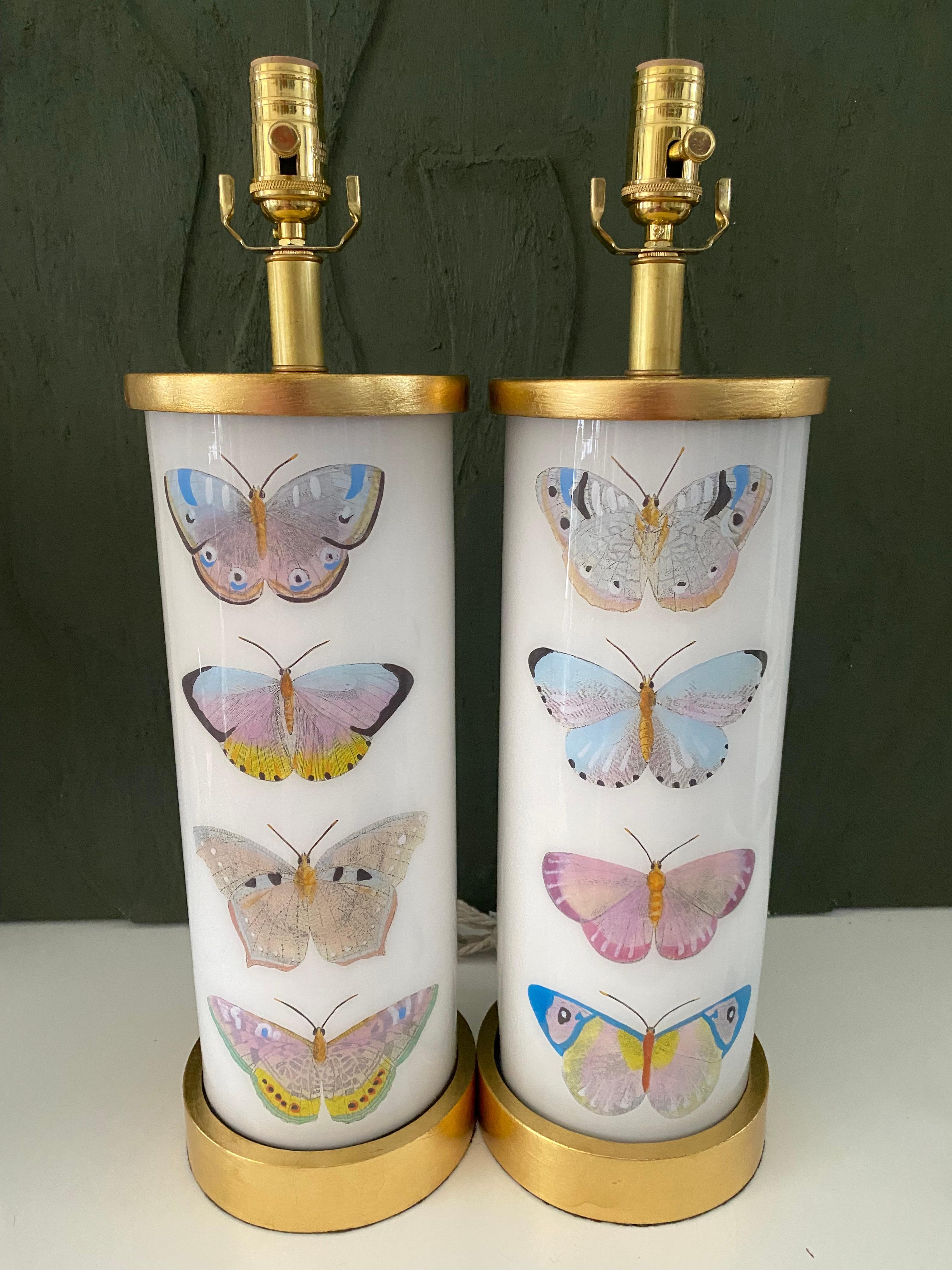 Hand made with care in Houston, Texas. This pair of glass lamps features a selection of 18th century hand-colored engravings of beautiful pastel butterflies, with hand turned with hand-turned gilt wood base and cap, polished brass dimmer socket and