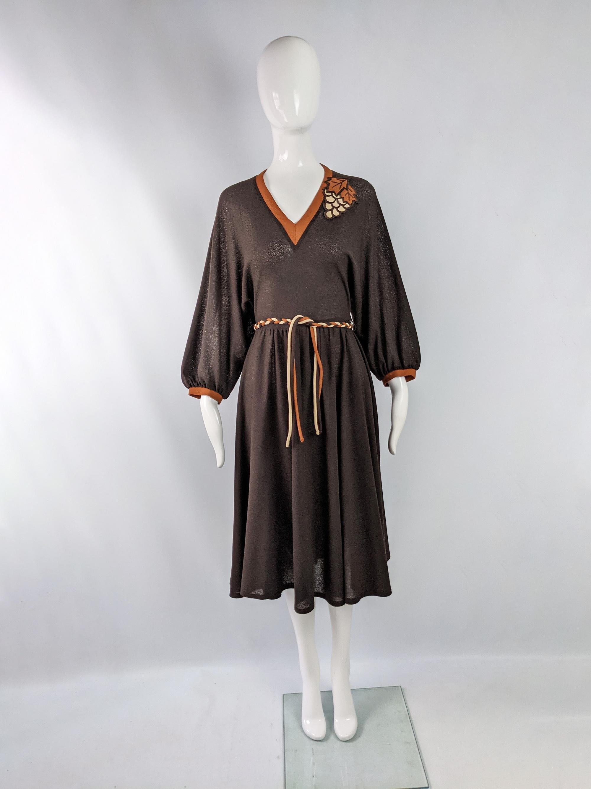 A fun and cute vintage womens dress from the 70s by quality English label, Liza Peta. In a brown, sheer crepe fabric with puffed dolman sleeves, a loose fit on top and a sweet grape embroidered applique on the shoulder.

Size: Marked vintage 12 but