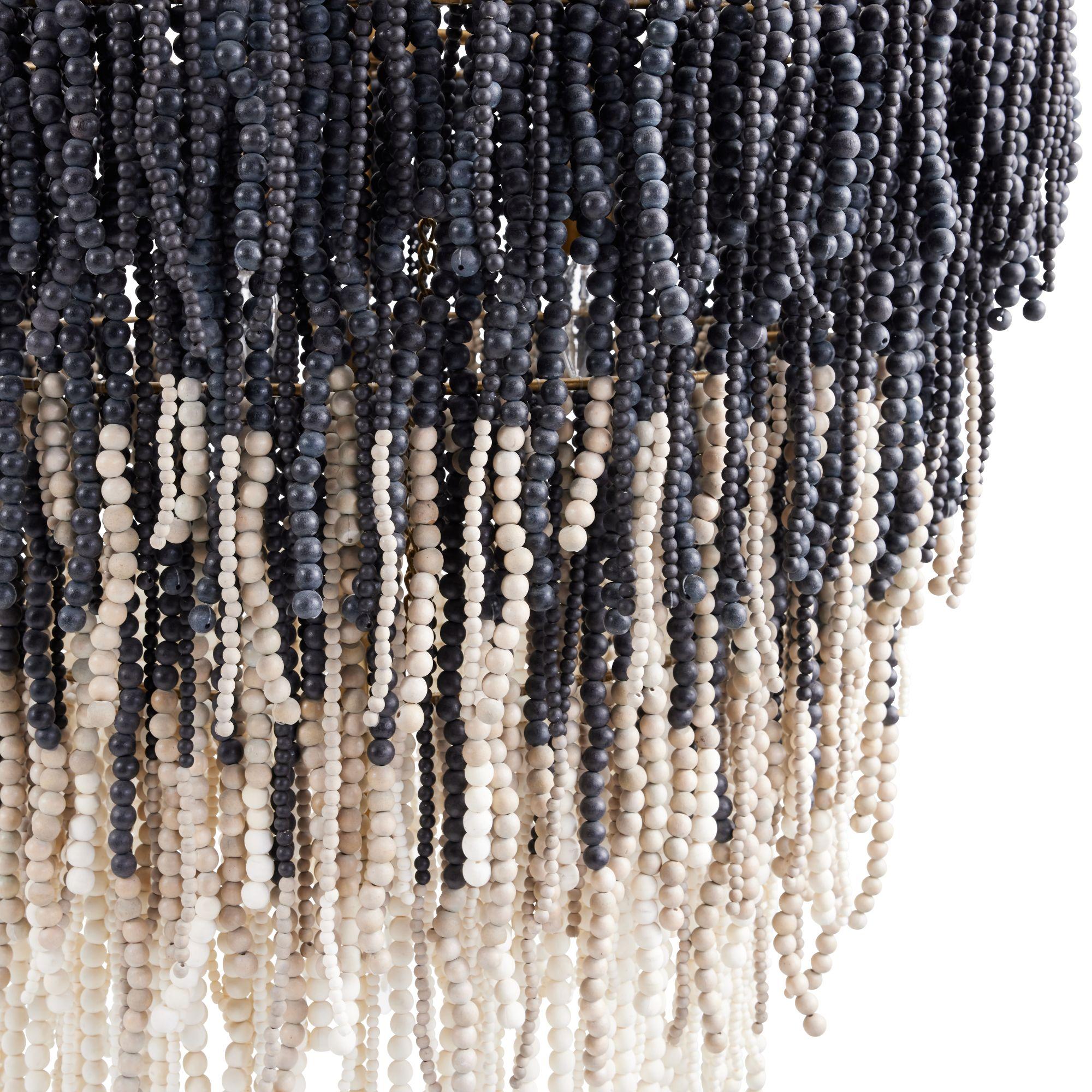 Lizzy Chandelier
Showcasing exceptional design and materials, the Lizzy Chandelier features four tiers in a layered, concentric construction, meticulously crafted from black, gray, and white wooden beads. These are artfully strung from an antique