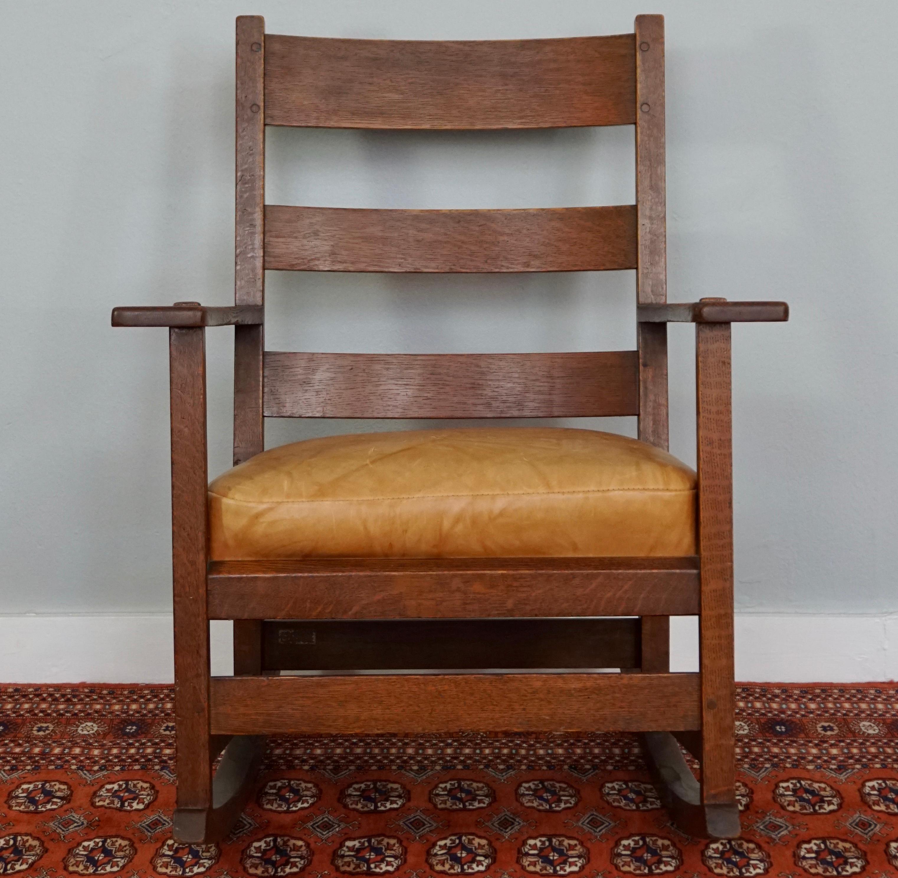 Arts & Crafts solid quarter sawn oak with leather cushion. “Work Of L&JG...” decal. Drop in original cushion with newer leather, three horizontal slats to back with original finish (cleaned) Very good condition and tight. A great daily rocker, circa