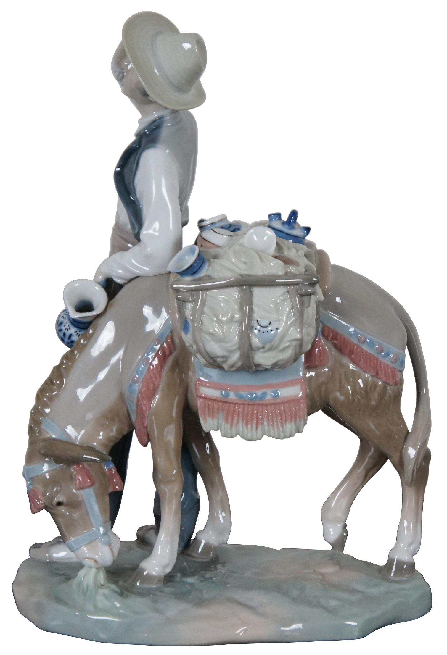 Vintage Lladro Spain porcelain figurine #4859 “Typical Peddler” showing a man leading a donkey laden with a large basket full of crockery. Produced between 1974 and 1985.
 