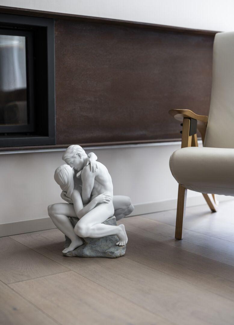 White satin-finished porcelain sculpture of a couple kissing sitting on a rock decorated with blue and green enamels. A couple's passion and love, captured as never before by Lladró. A piece of great sculptural prowess and technical complexity, in