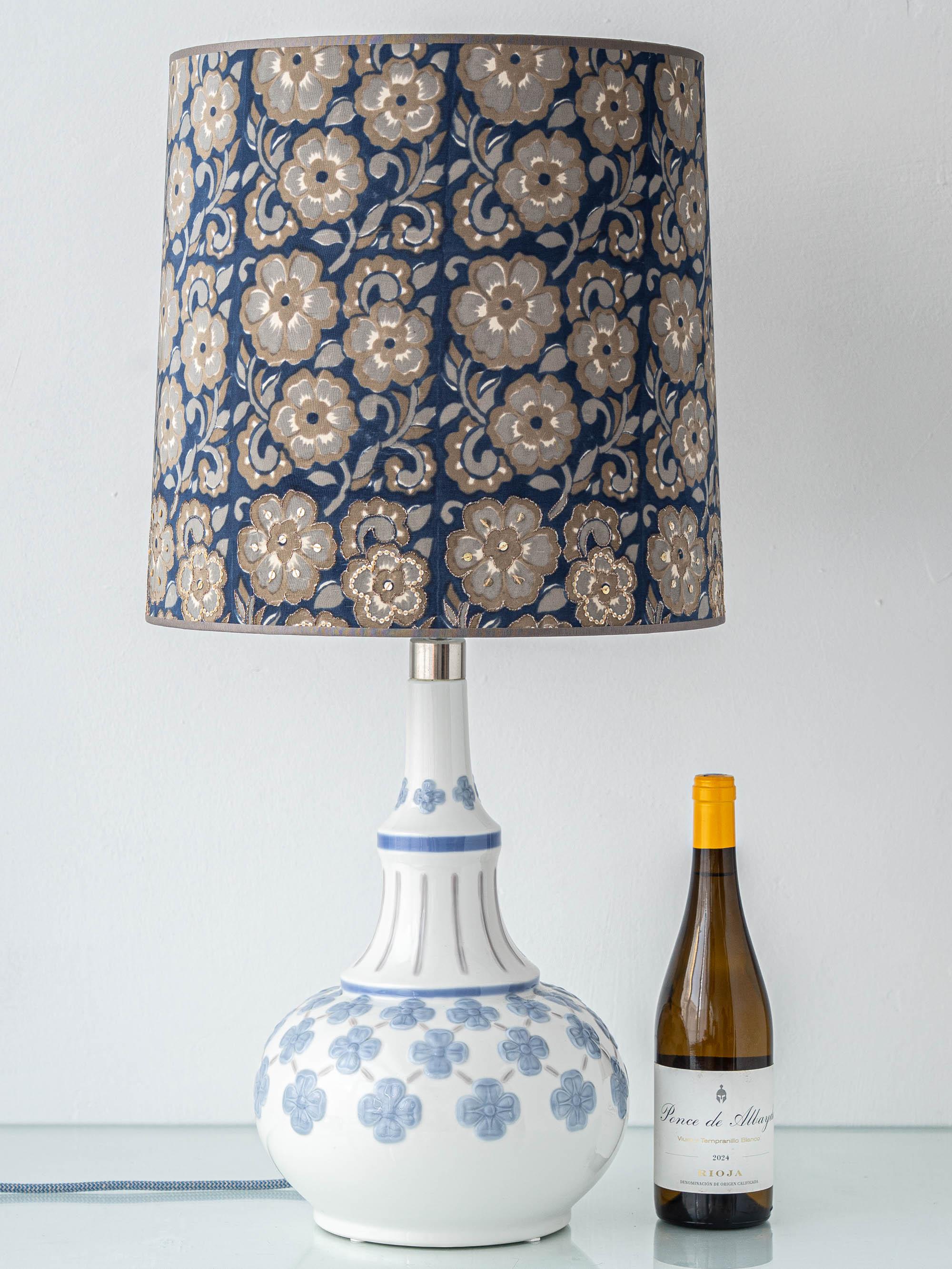 Kornblumenblaue und weiße seltene Vintage-Lladró-Keramik-Tischlampe mit erhabenem Blumenrelief und einem neuen marineblauen, taupefarbenen und champagnerfarbenen bestickten Lampenschirm aus einem Vintage-Seidensari von Amitābha Studio.

Der