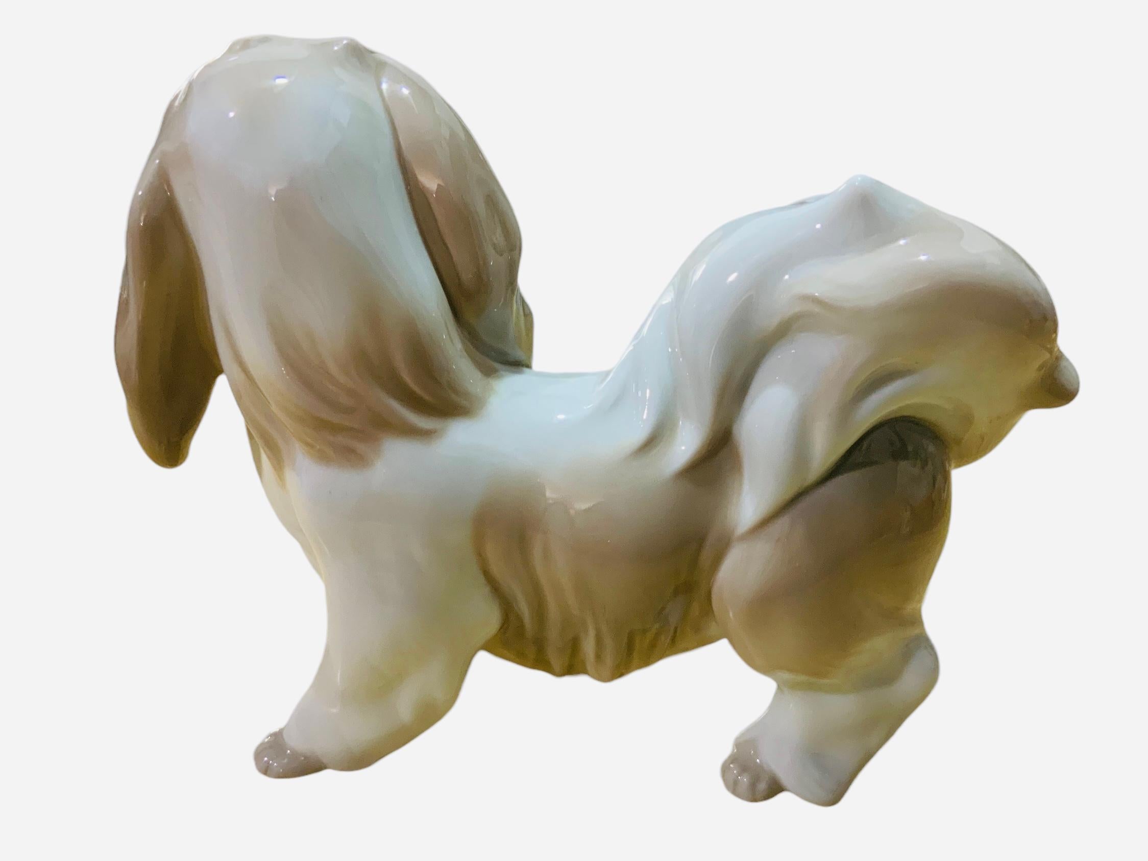This is a Lladro porcelain figurine of a dog. It depicts a very well done hand painted white and light brown dog. The Lhasa Apso is standing up with a lot of wavy hair and a “I don’t care” gaze. The Lladro hallmark is below the figurine.