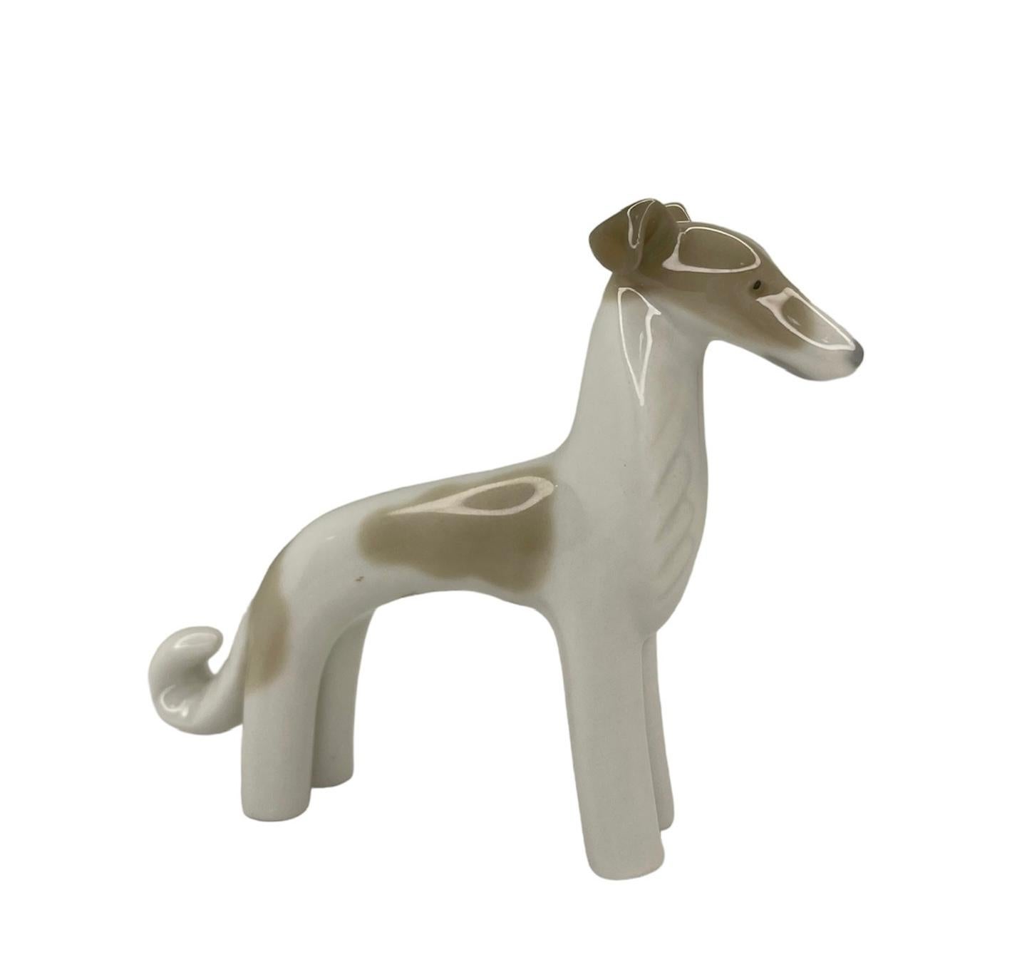 This is a Lladro porcelain mini figurine of a dog. It depicts a hand painted brown and white dog standing up and very contemplative. The Lladro Nao hallmark is below the figurine.