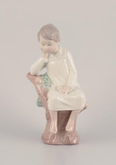 Lladro, Spain. Porcelain figurine of a girl sitting on a tree stump.
