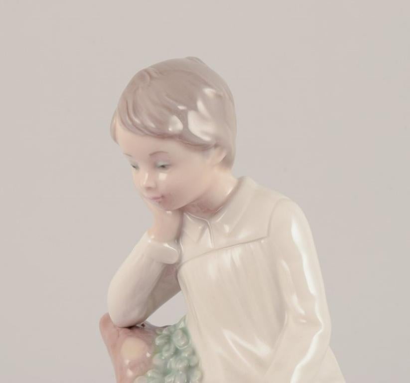 Lladro, Spanien. Porzellanfigur eines Mädchens, das auf einem Baumstumpf sitzt.  (Ende des 20. Jahrhunderts) im Angebot