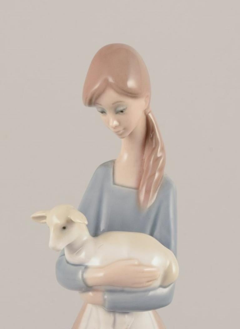 Spanish Lladro, Spain. Porcelain figurine of a standing young woman holding a lamb. For Sale