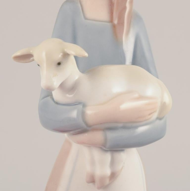 Lladro, Spain. Porcelain figurine of a standing young woman holding a lamb. In Excellent Condition For Sale In Copenhagen, DK