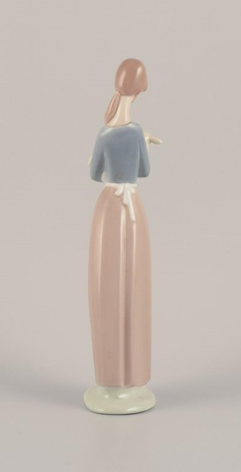 Late 20th Century Lladro, Spain. Porcelain figurine of a standing young woman holding a lamb. For Sale