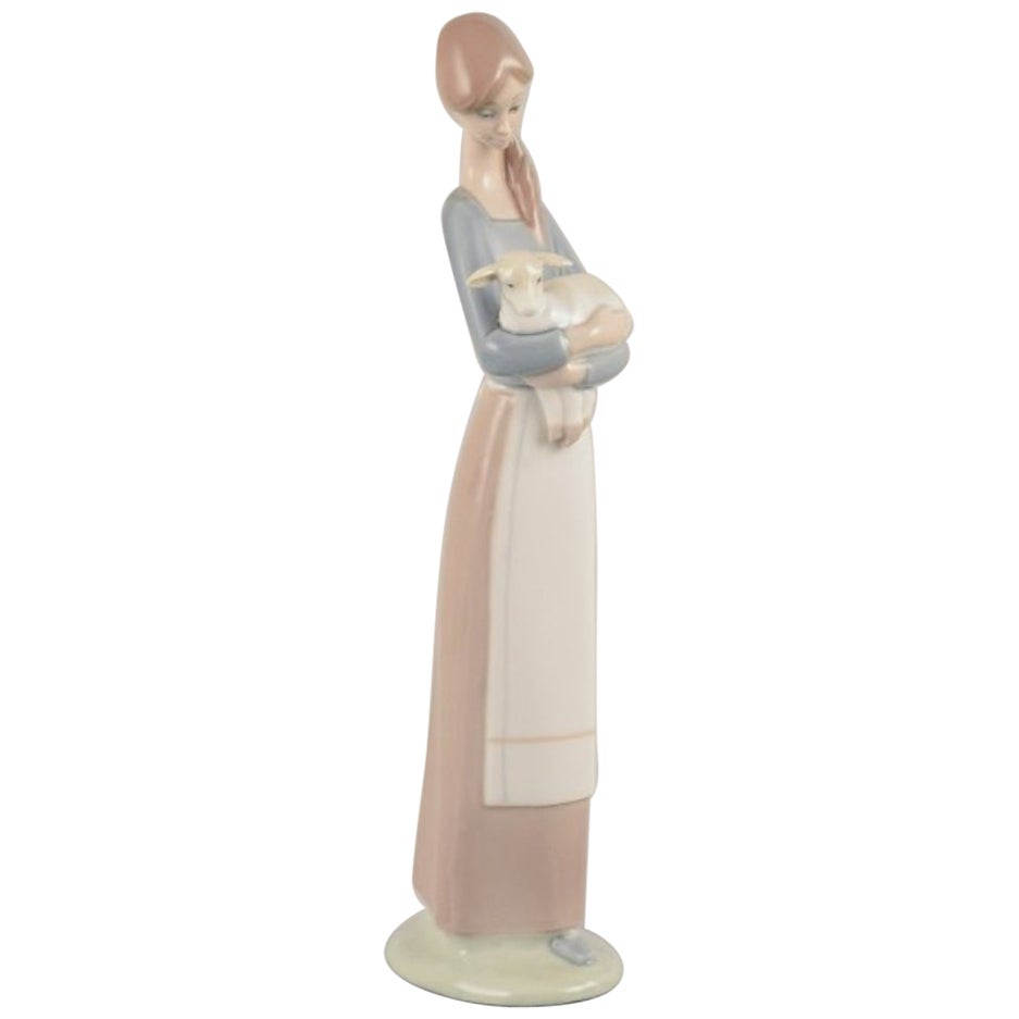 Lladro, Spain. Porcelain figurine of a standing young woman holding a lamb.
