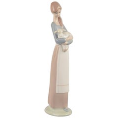 Lladro, Spanien. Porzellanfigur einer stehenden jungen Frau, die ein Lamm hält.
