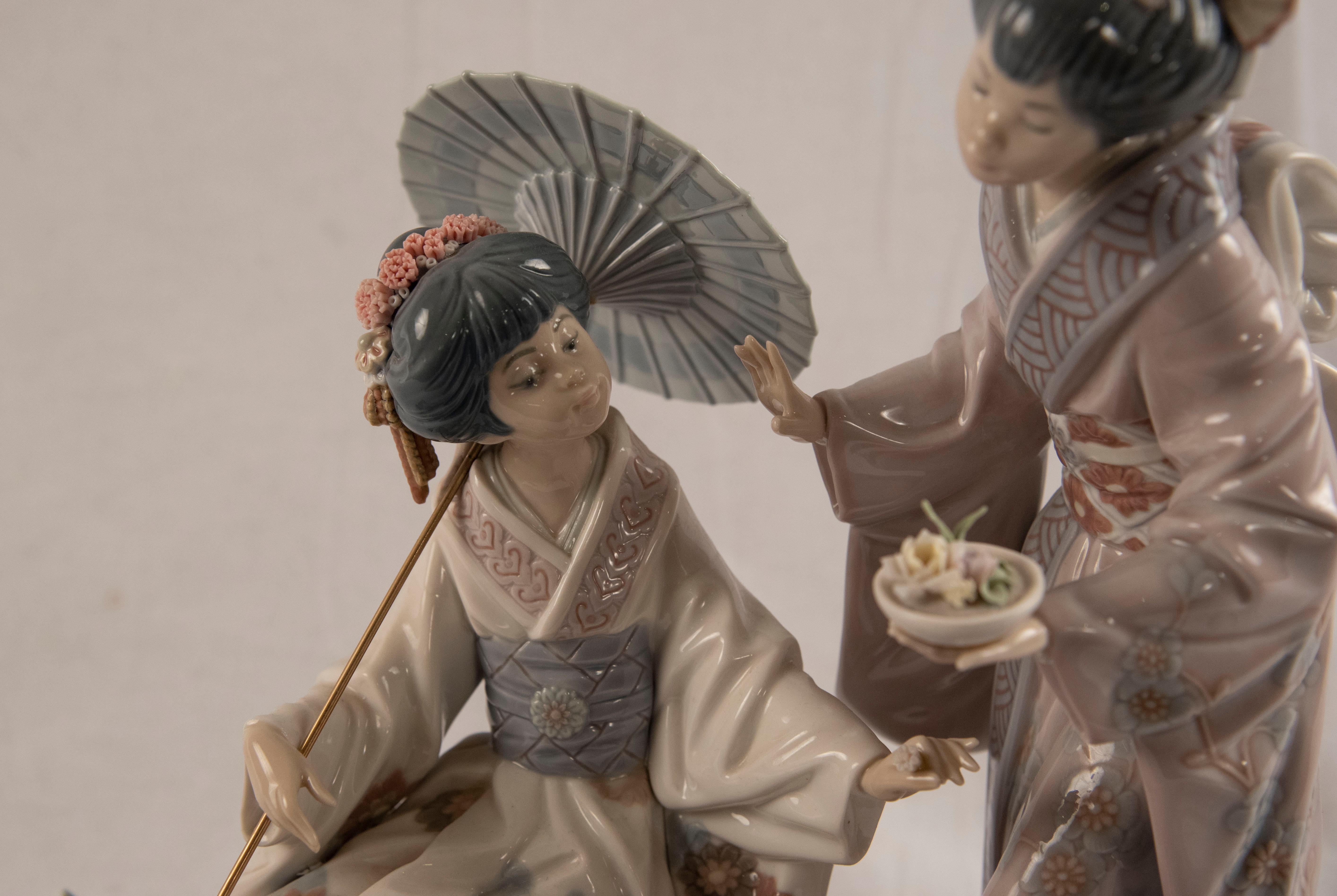 Glossy porcelain sculpture of Japanese women on a bridge with an umbrella decorated with handmade flower and floral motifs on a wooden base. Model #1445.