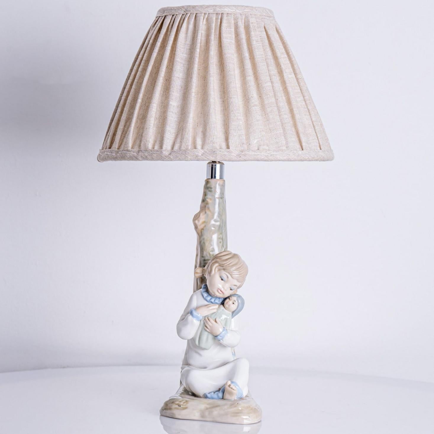Beautiful table lamp of a girl rocking a doll in her arms. Made of porcelain in Spain around the 1970s.

The beige shade fits perfectly with the soft colors of the porcelain base.

 ;

