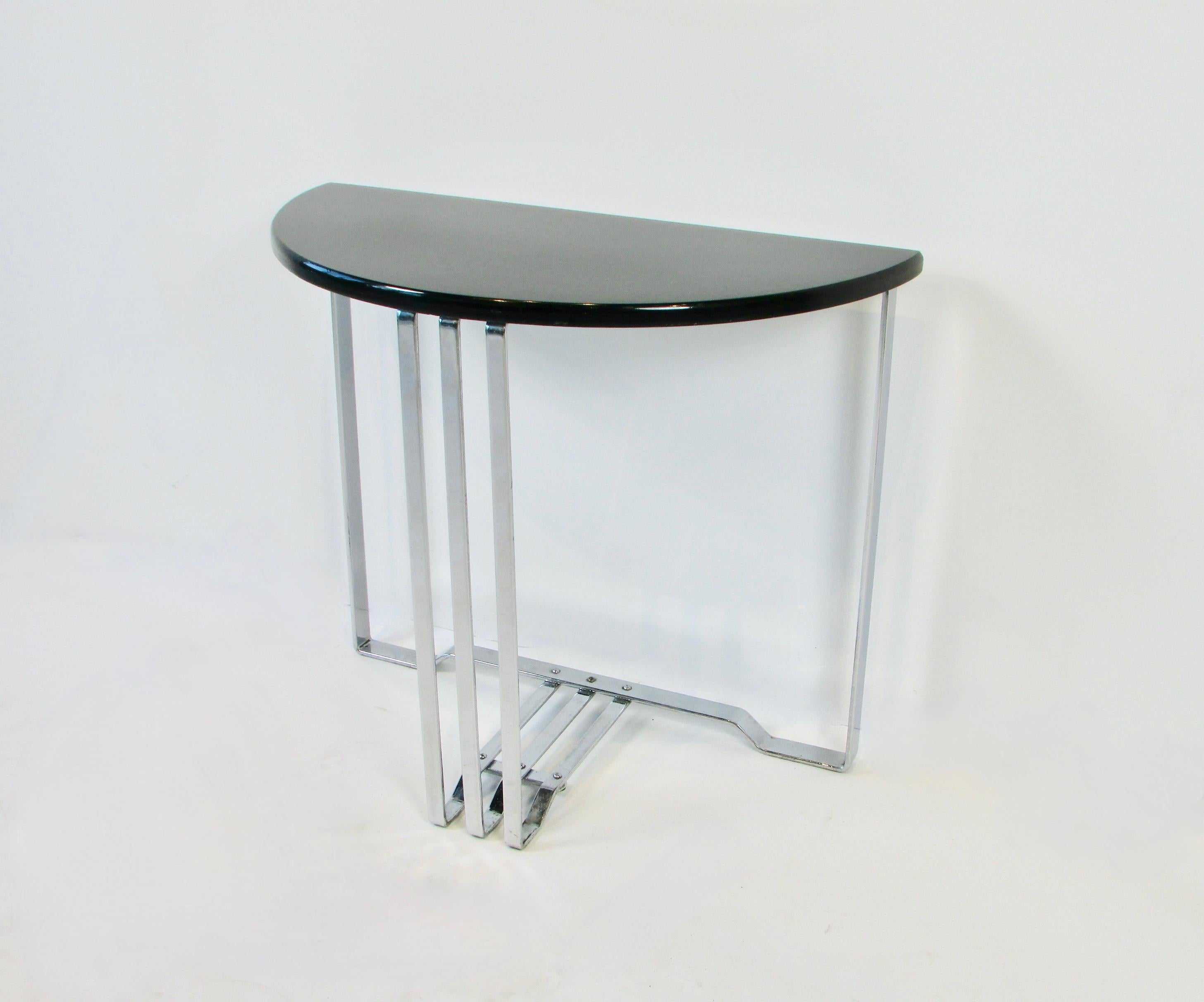 Black lacquered demi lune top on banded chrome base. Manufactured by Lloyd Co of Menomee Mi. Attributed to Wolfgang Hoffman but may be Alfonse Bach Both designed for Lloyd in the 1930s. The table is in completely original finish. Chrome shows well