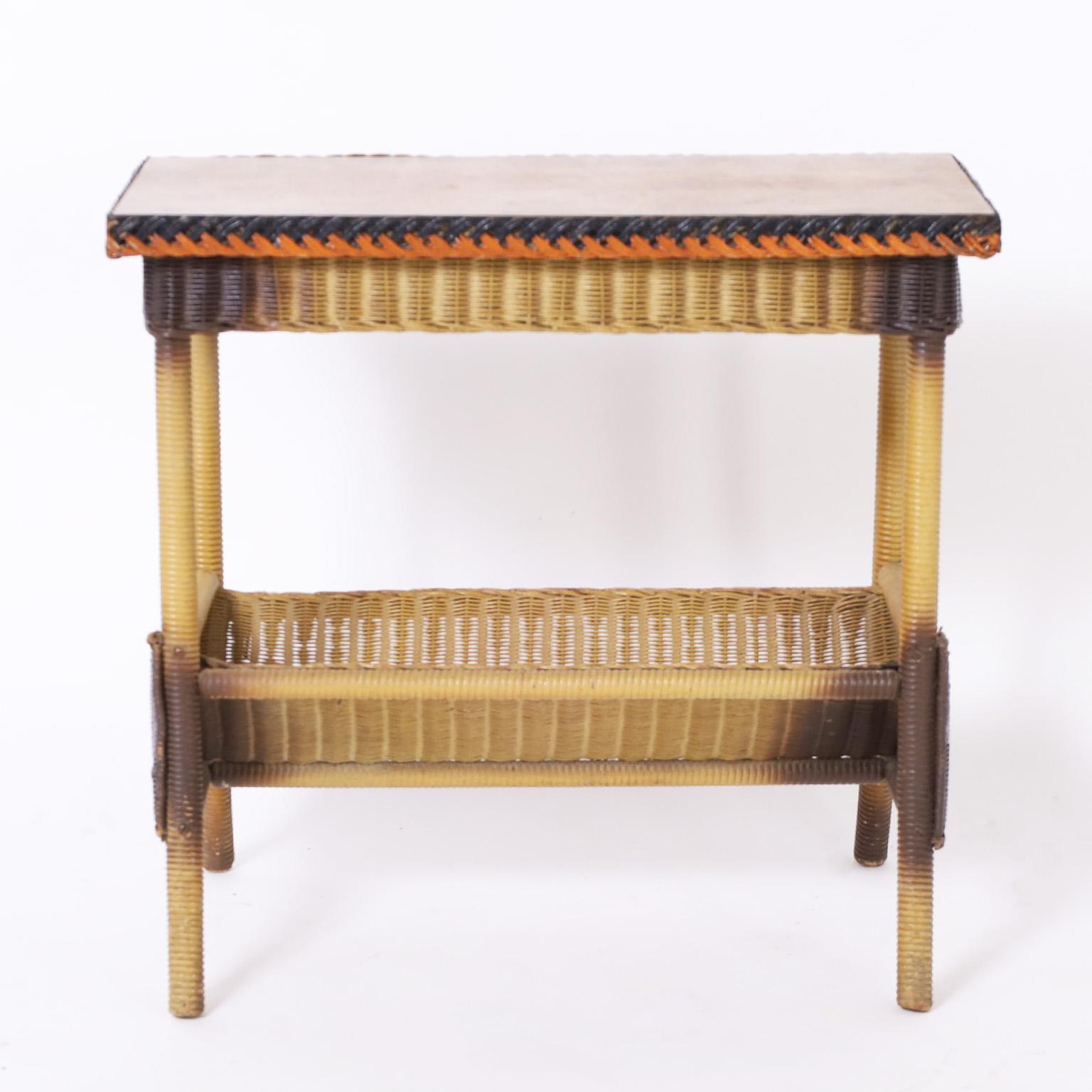 Rare and remarkable side table crafted in wicker with an unusual form having a magazine or book rack below and all of the original paint and remnants of a Lloyd Loom label on the bottom.