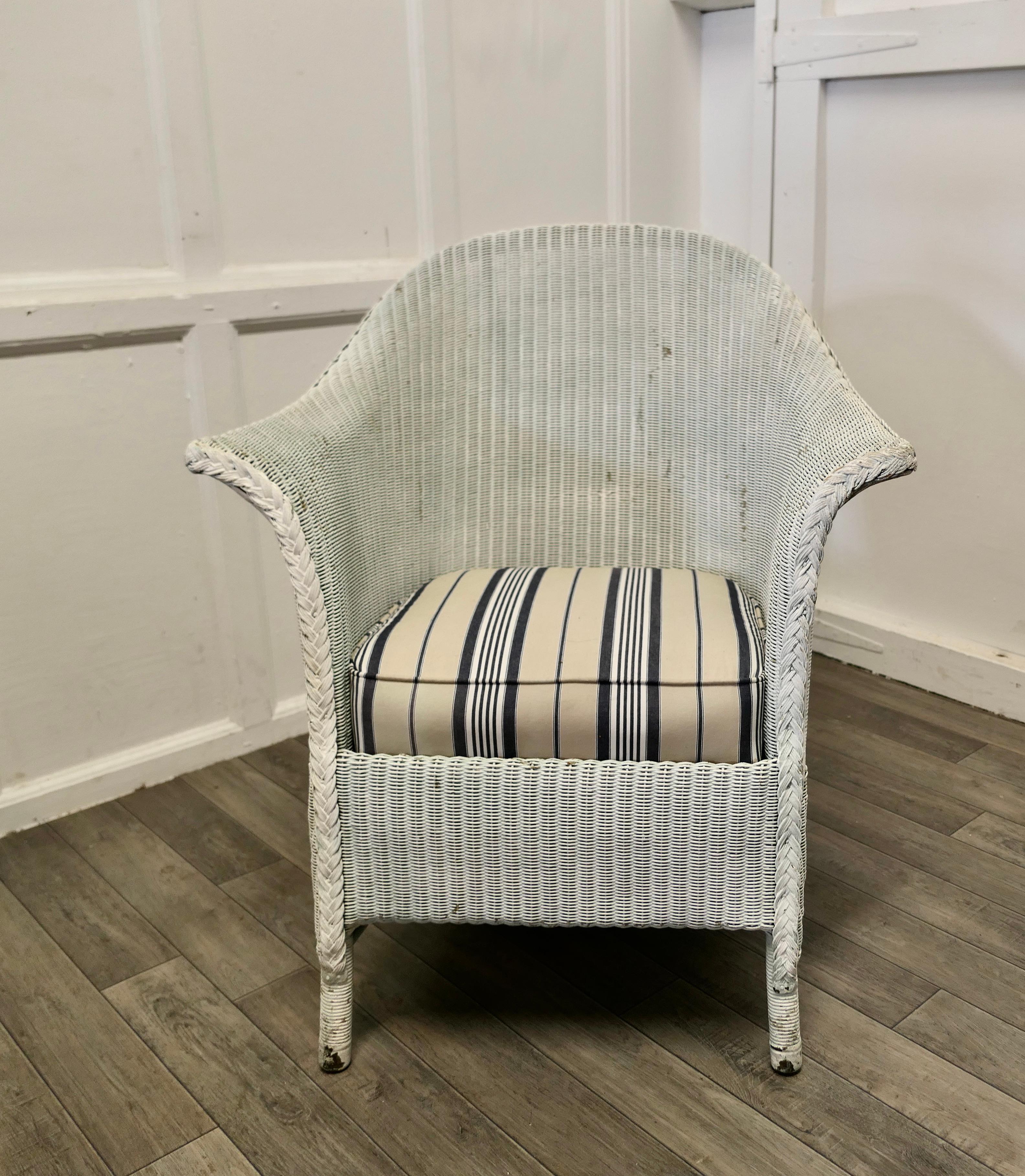 Lloyd loom easy chair. 

This delightful Shabby Lloyd Loom Arm Chair dating from the early 20th century. 
The chair is a generous sweeping shape and has a comfy sprung seat which has new upholstery in a seaside Linen Stripe.
The chair is sound,