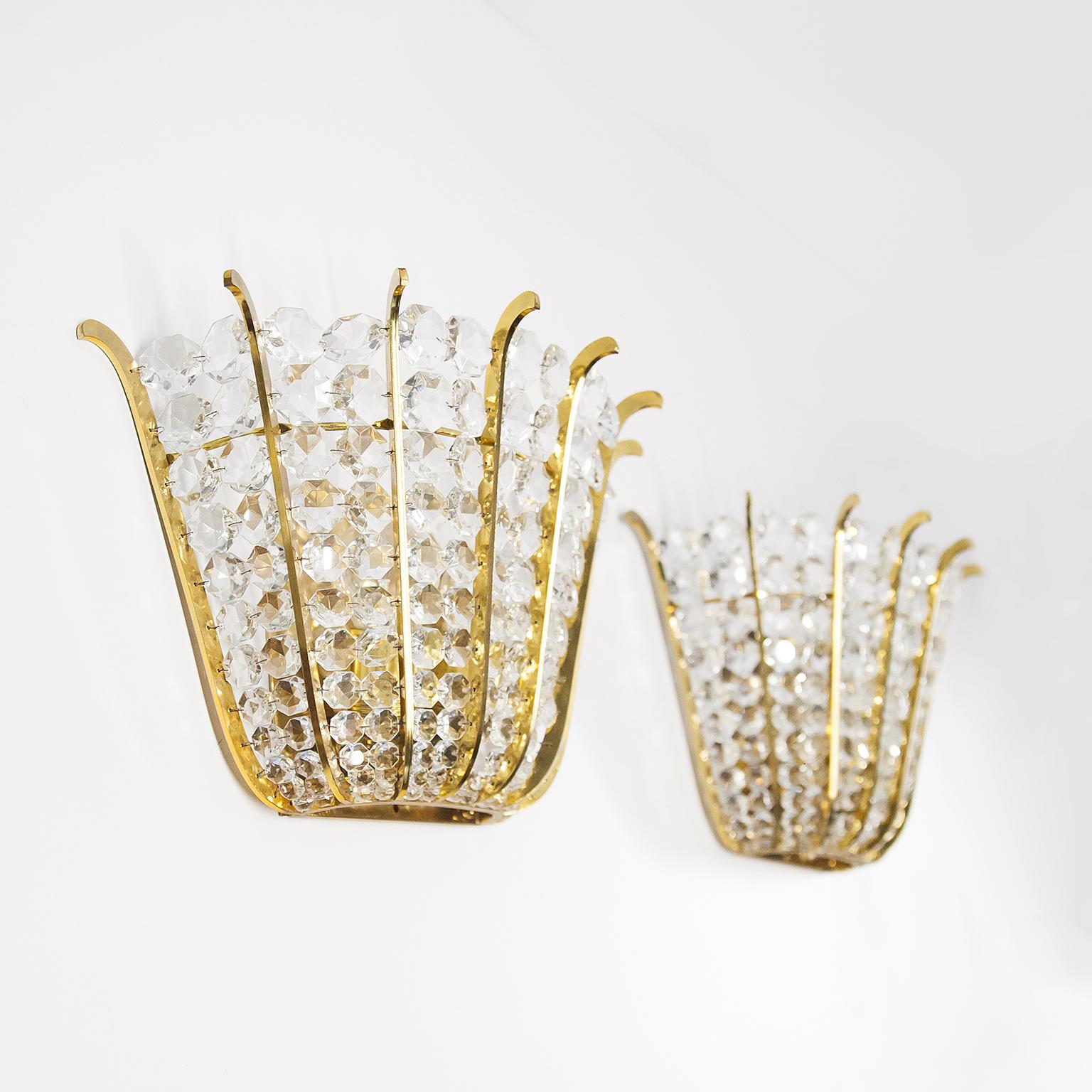 Elegante juego de dos apliques de cristal facetado y marco de latón macizo de Lobmeyr Viena, Austria, años 60. Diseñadas con anillos de latón dorado y equipadas con más de 100 cristales tallados a mano y facetados, estas lámparas crean una impresión