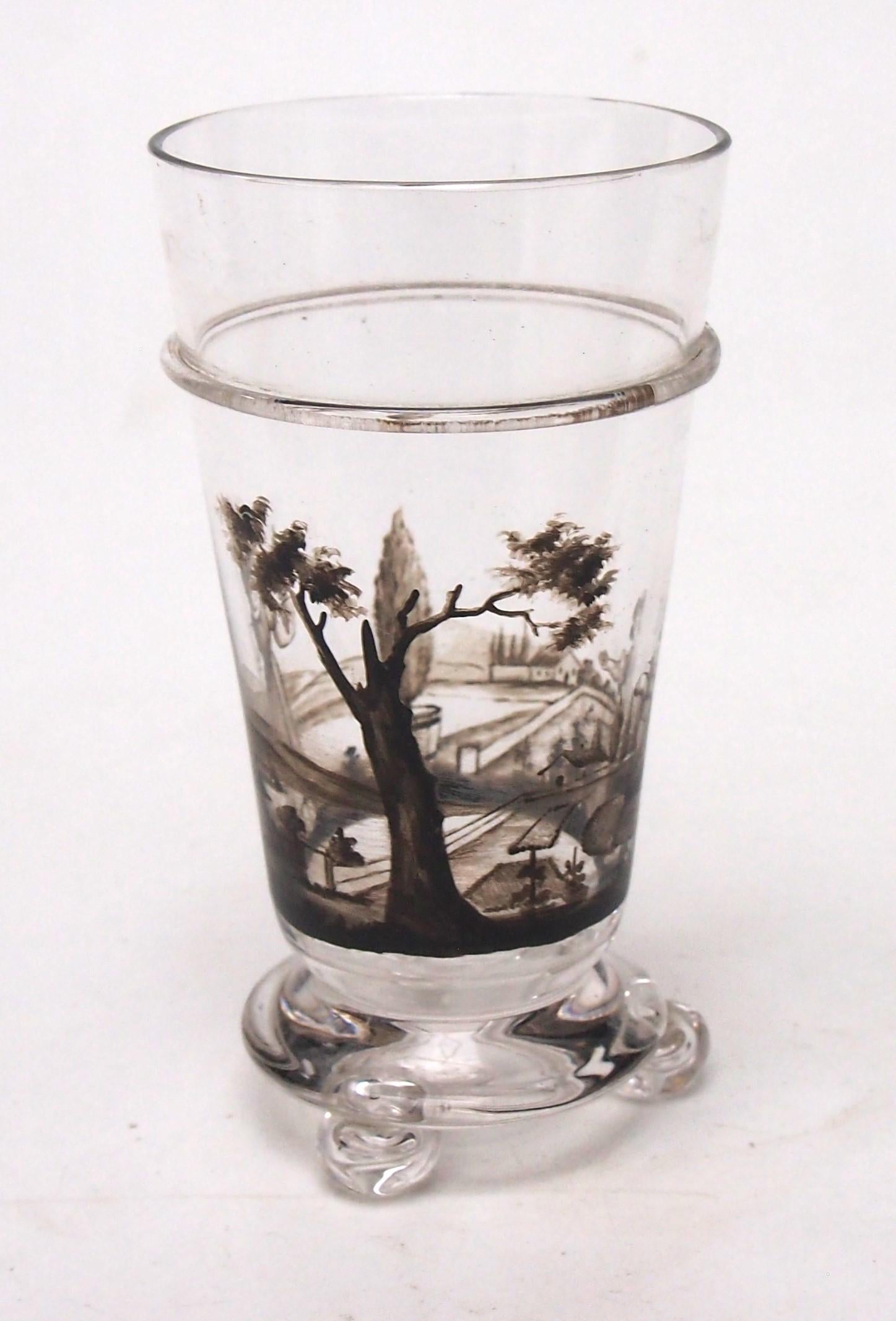 Fabulous and rare glass miniature -a glass or small vase -with 3 small ball feet and hot applied ring band by J & L Lobmeyr c1890. Enamelled in Black with two ladies working an a formal garden with a large old tree - one lady with a watering can and