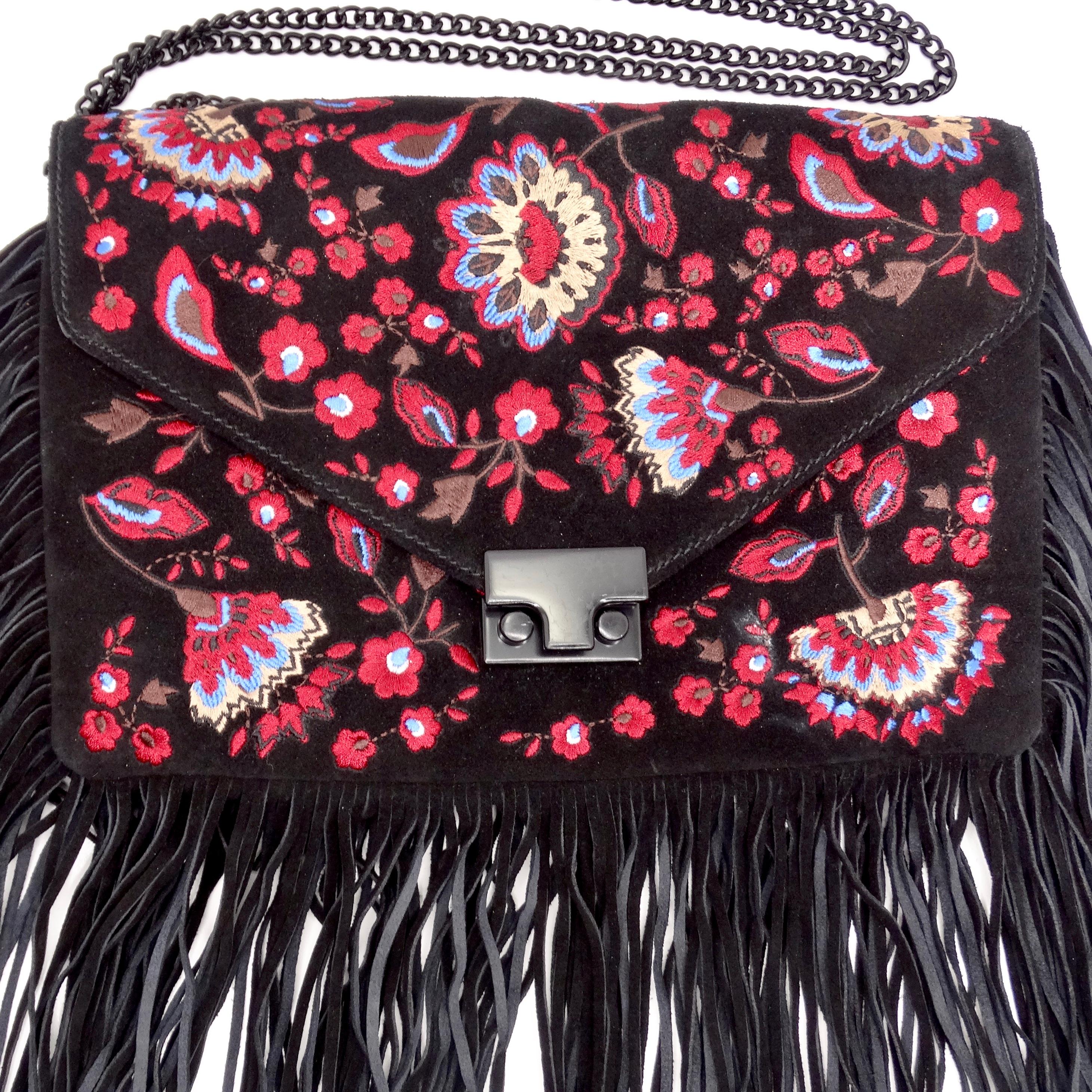 Introducing the Loeffler Randall Embroidered Suede Fringe Handbag, a vibrant and bold statement piece that exudes bohemian charm and effortless style. Crafted from luxurious black suede, this fold-over handbag features stunning multicolor floral