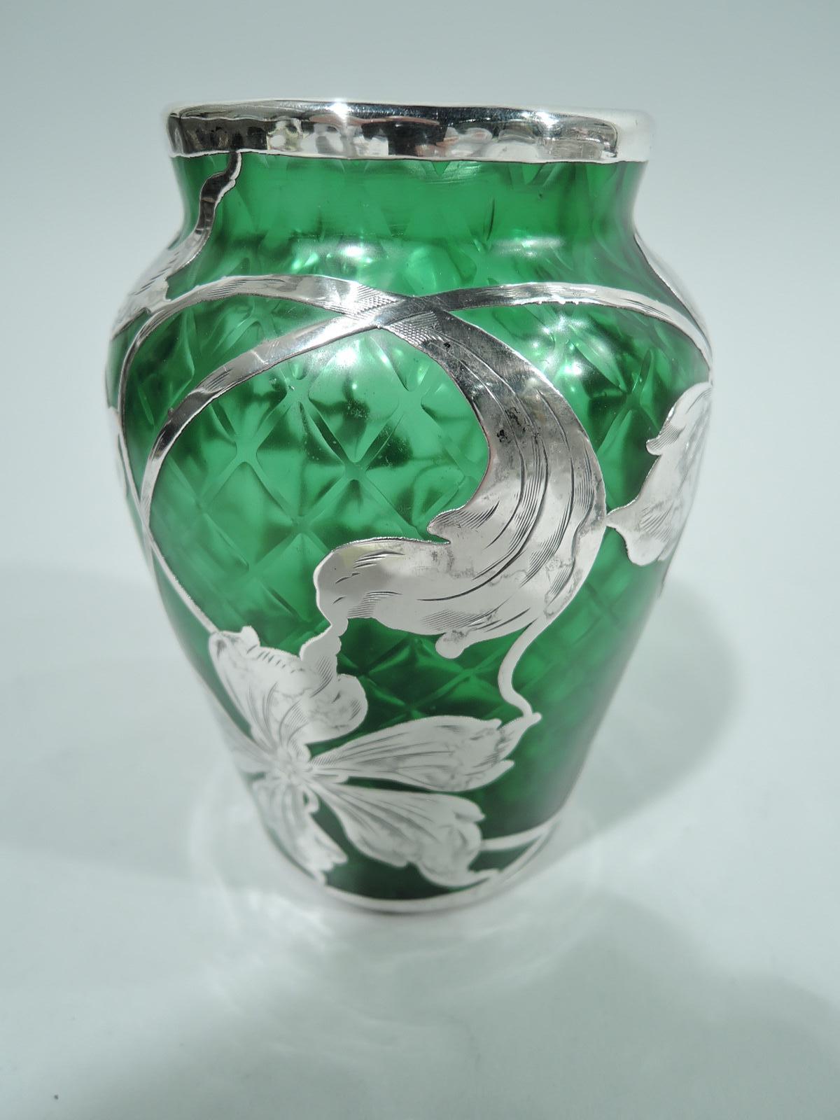 Turn-of-the-century Art Nouveau glass vase by historic Loetz with engraved silver overlay. Tapering sides, curved shoulder, and short straight neck. Overlay in form of loose, floaty flower heads and tendrils. Glass green and quilted. Pontil mark.