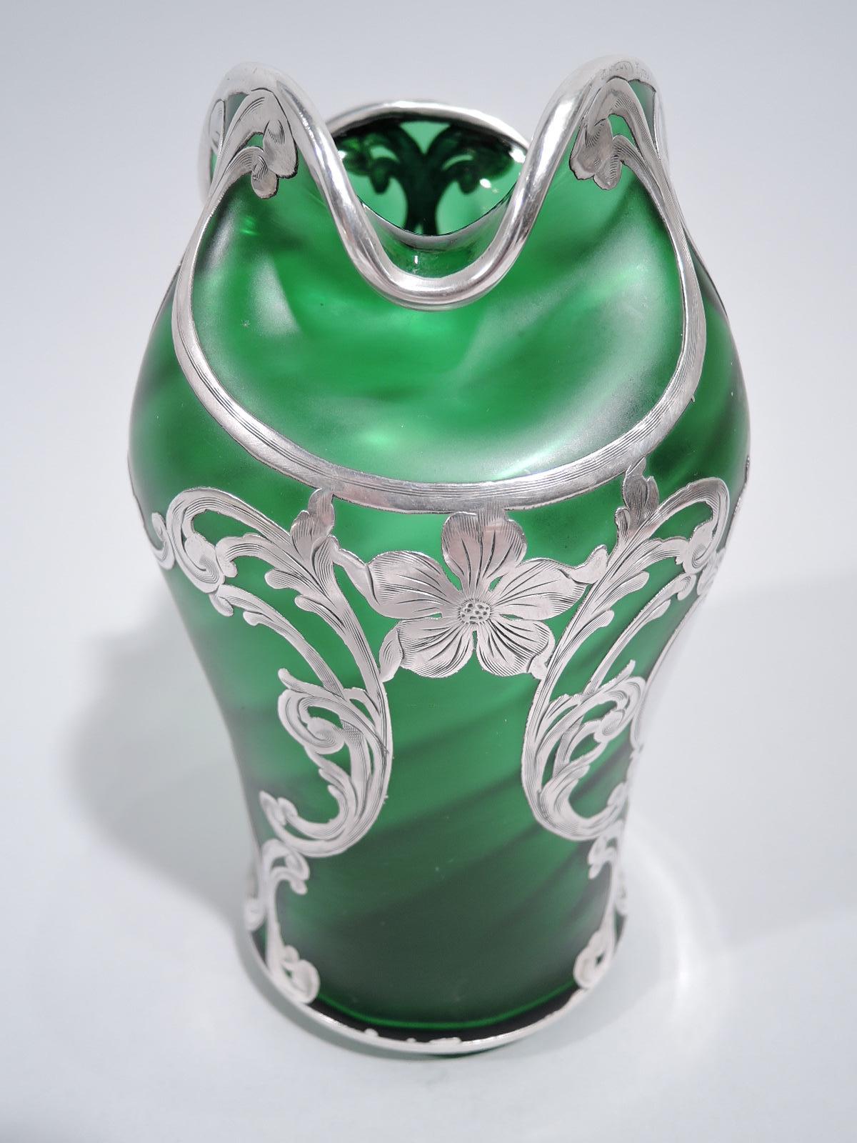 Turn-of-the-century Art Nouveau glass vase by historic Loetz with engraved silver overlay. Gentle bombe body with turned-down trefoil mouth. Overlay in form of scrolled frames joined by flower heads, and oval cartouche (vacant). Glass green with