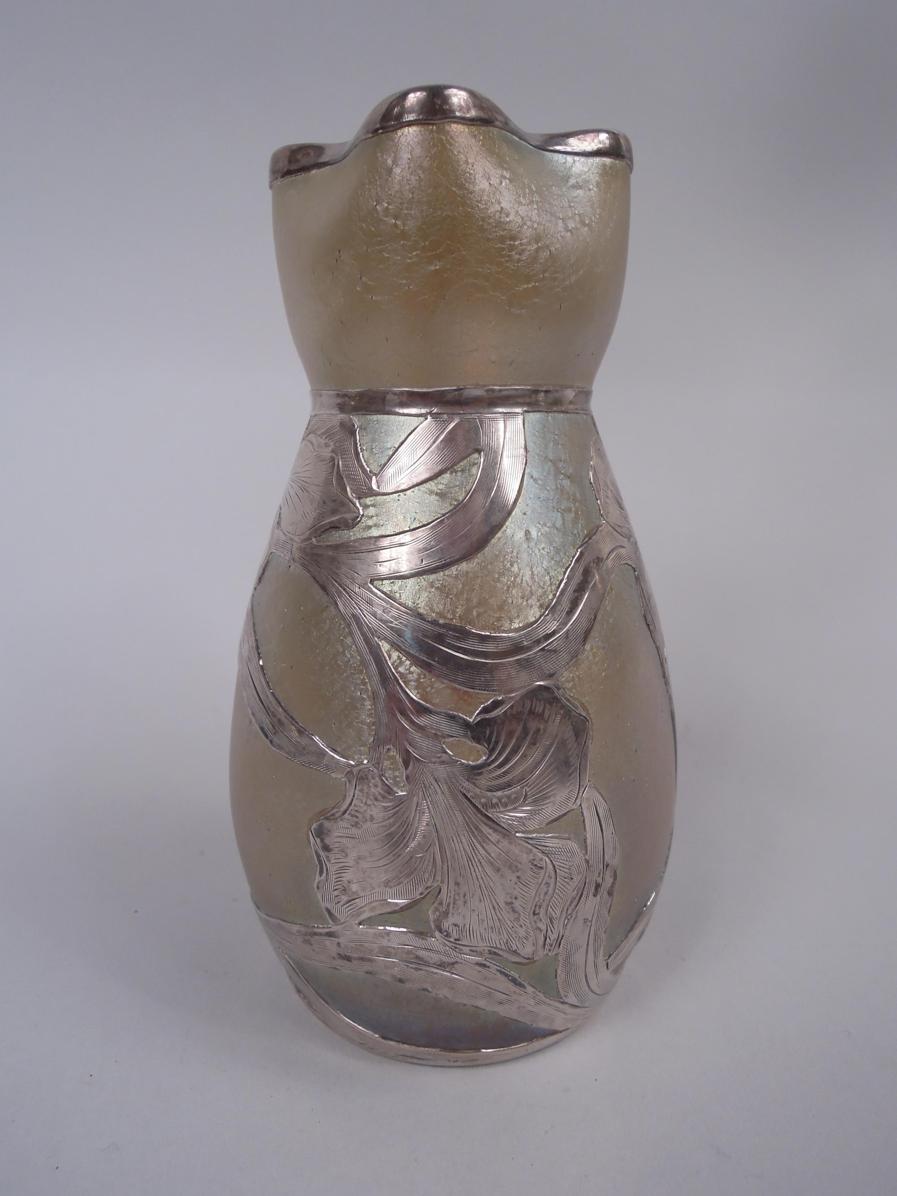 Vaso in vetro Art Nouveau con sovrapposizione di argento inciso, 1900 circa. Ciotola ovoidale con bocca arricciata e a trifoglio. Sovrapposizione di viticci e capolini sciolti e intrecciati. Vetro giallo iridescente. Marchio Pontil. Vetro di Loetz