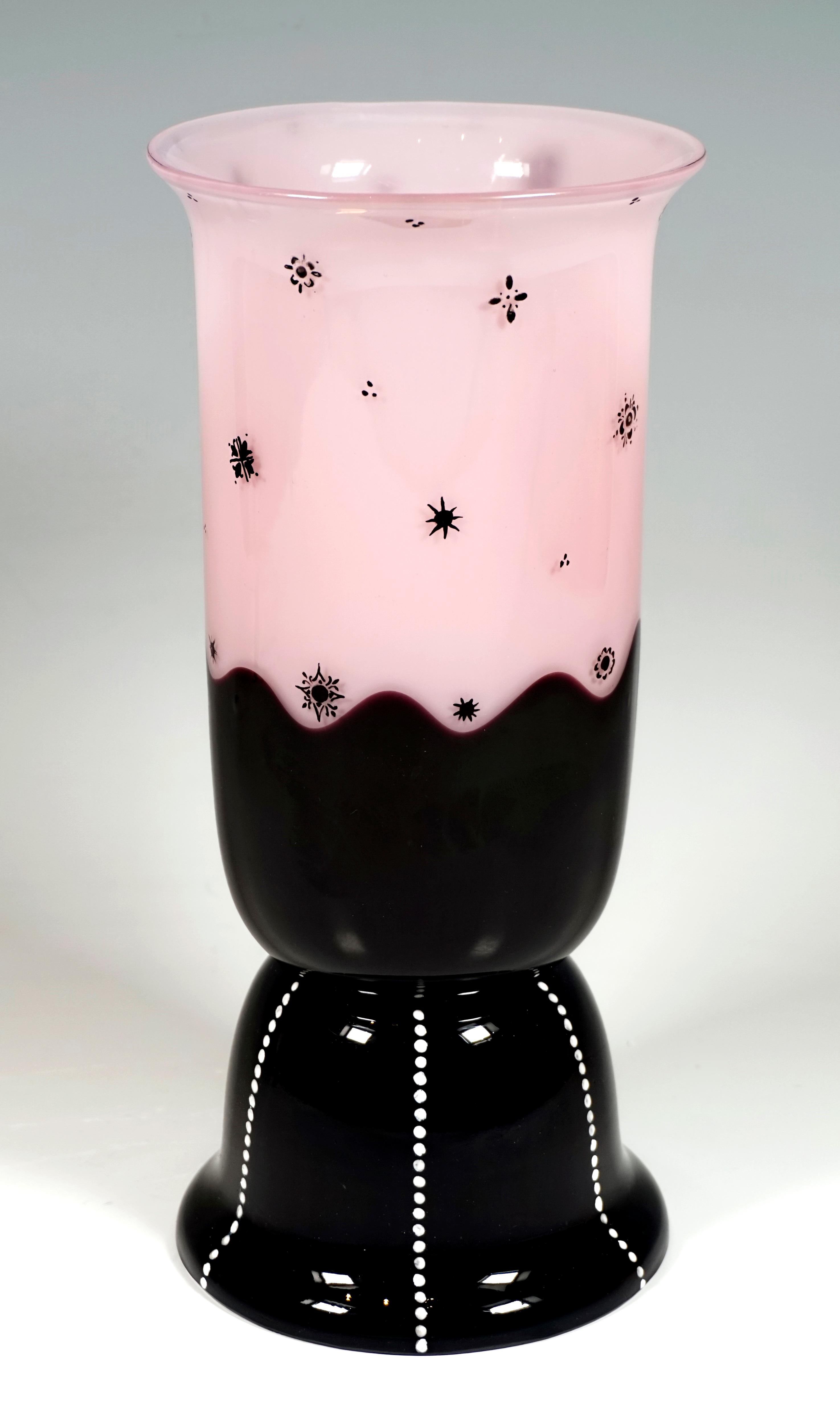 Body blown in a model, cylindrical with flared mouth rim, constriction in the lower third, forming a stepped, high arched base with flared rim, object divided in the middle by a wavy line into 2 colored areas: lower area black, upper area opal pink