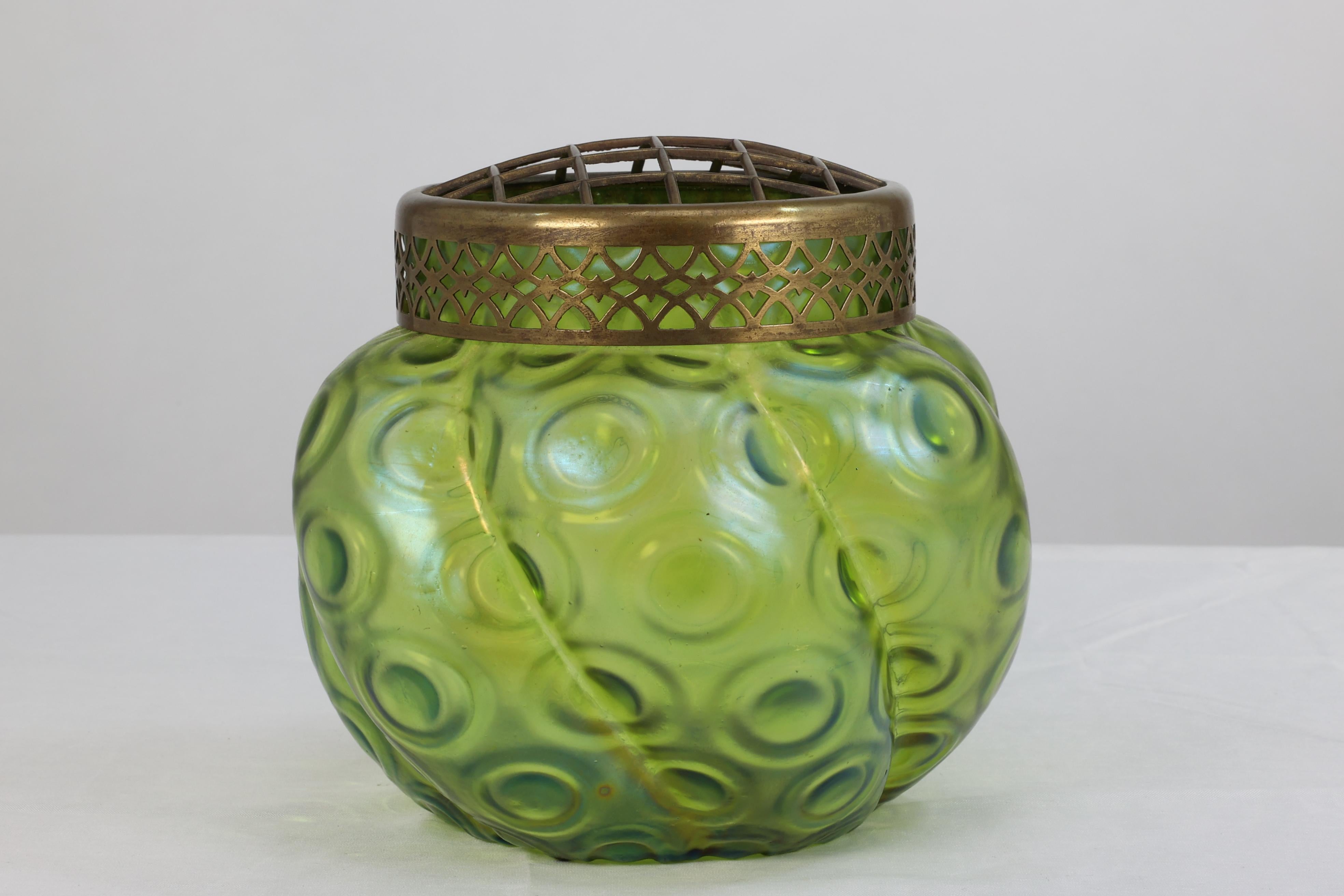 Loetz, attributed. 
An Art Nouveau green glass flower holder with circular swirling decoration to the body glass, with its original brass flower arranging top.


 