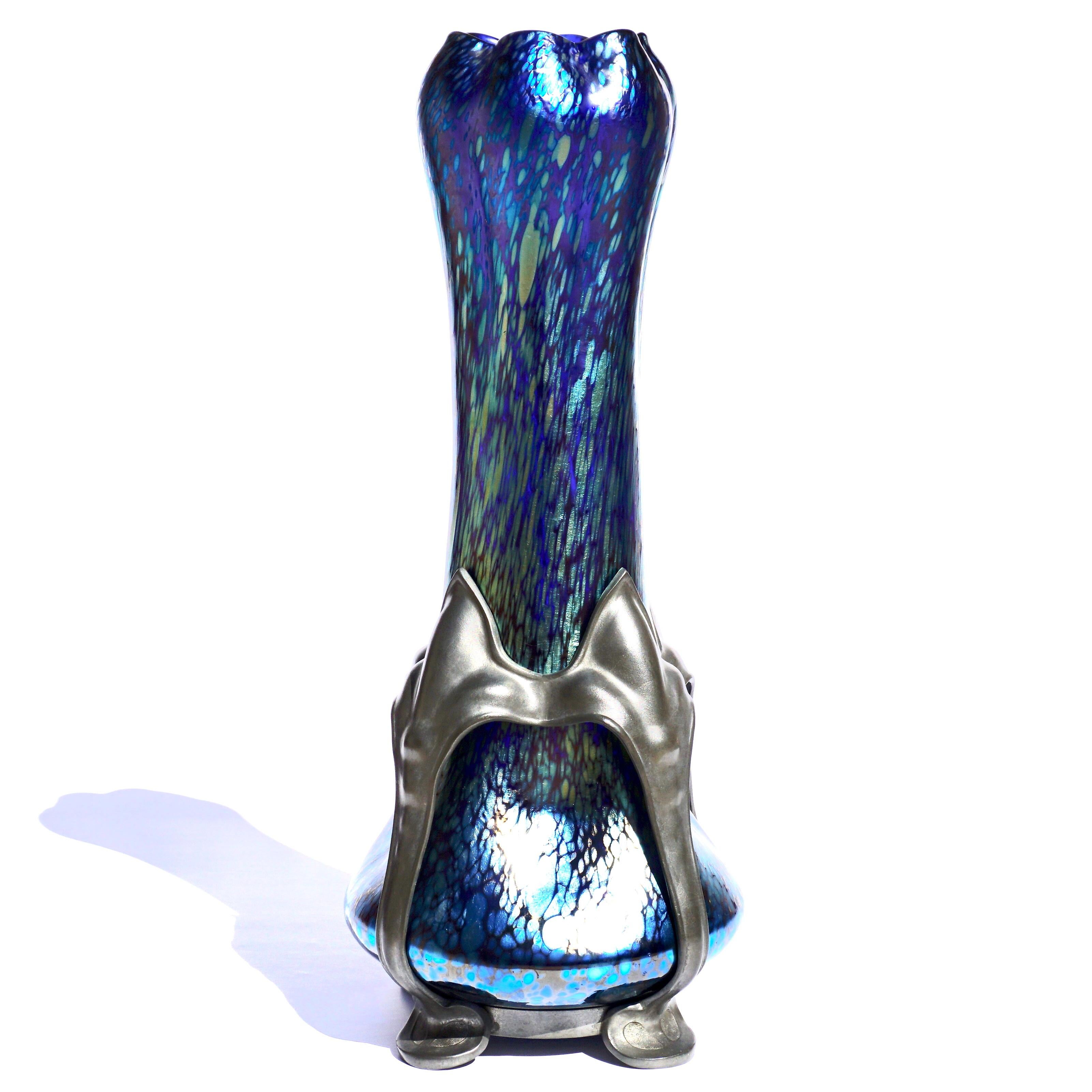 A Loetz Cobalt Papillon Art Glass and Pewter Art Nouveau Vase. Circa 1900

The shapely design with flared base having four evenly spaced indentations below sloping sides rising to a swollen top crimped into six lobes, all finished in blue