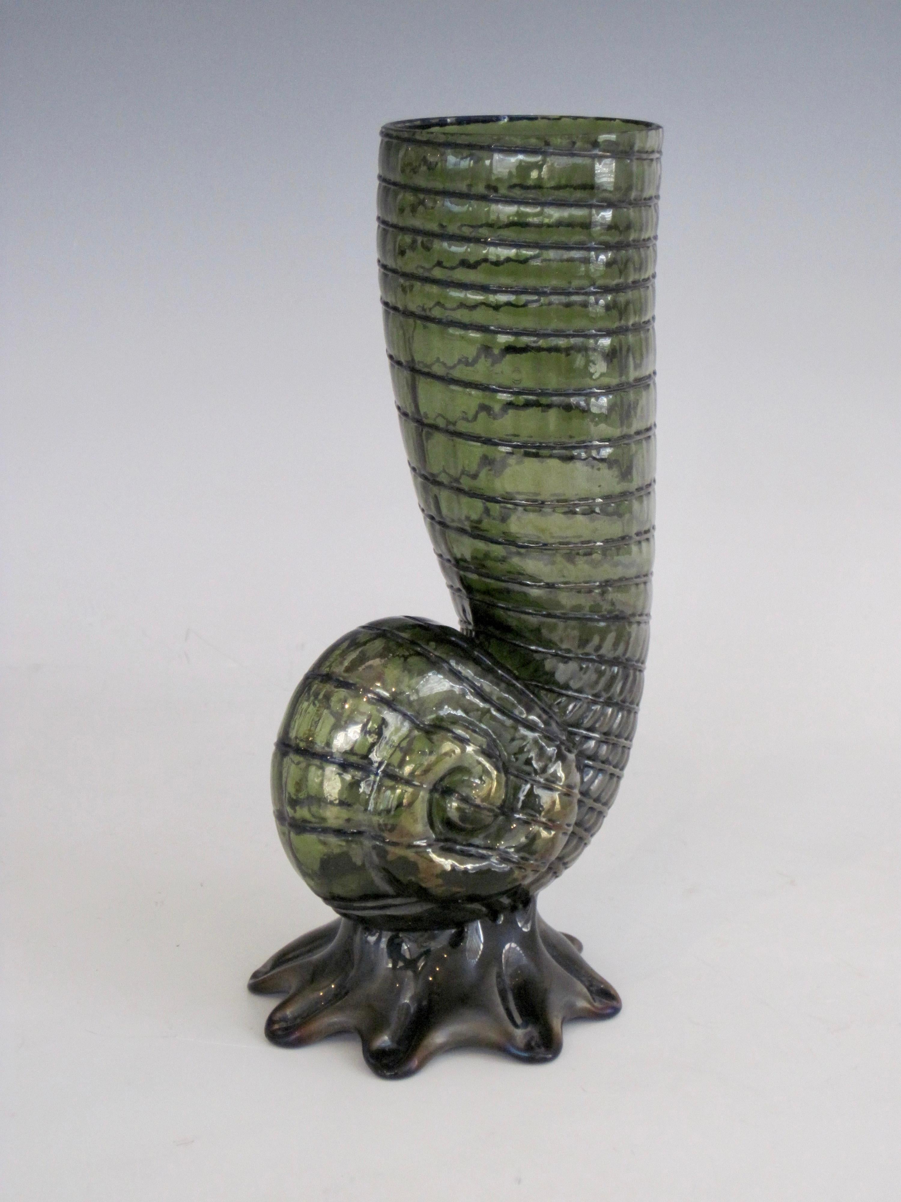 An Art Nouveau nautilus shell form flower bud vase by Loetz, Austria, circa 1900.

This hand blown elegant form in green art glass with thin blue-black stripes presents the feeling of upward movement. The blue-black foot gives the semi-transparent