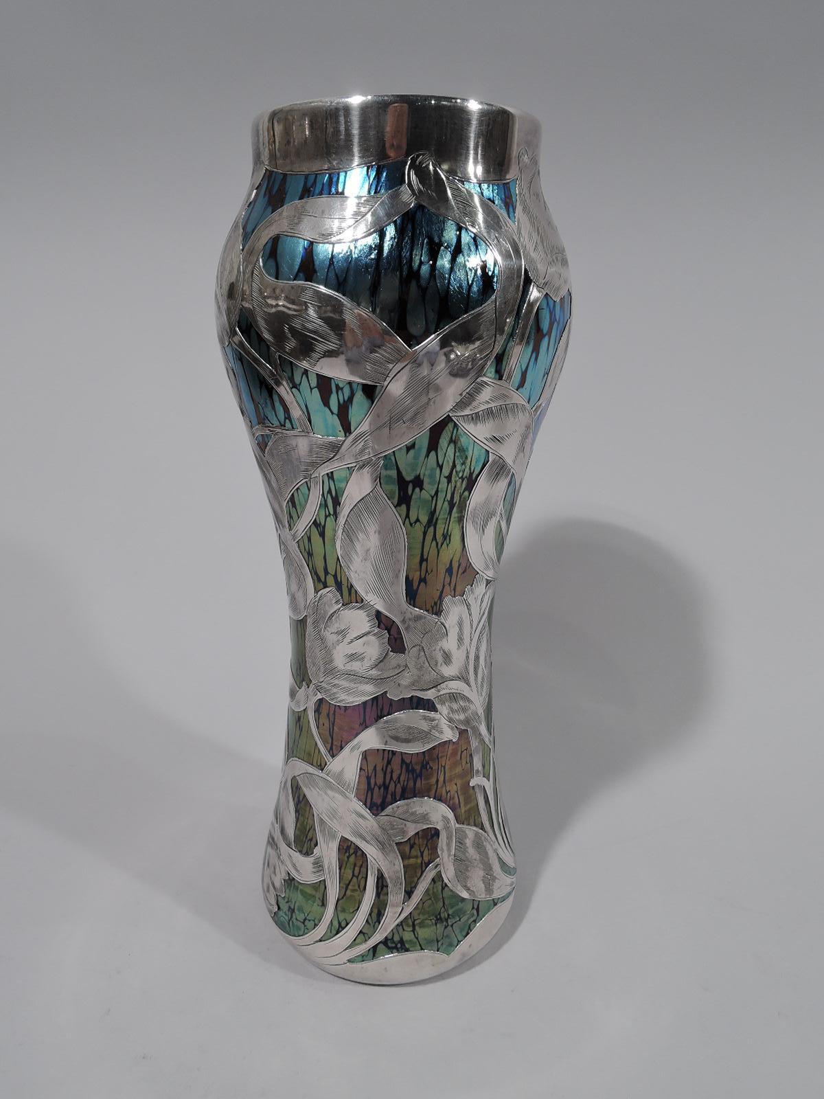 Art Nouveau glass vase by historic Loetz, circa 1910. Gentle baluster with short neck. Veined “oil patch” iridescence in blue shading to green. Engraved silver overlay in form of stem flowers with entwined ribbon tendrils. Loose and fluid with nice