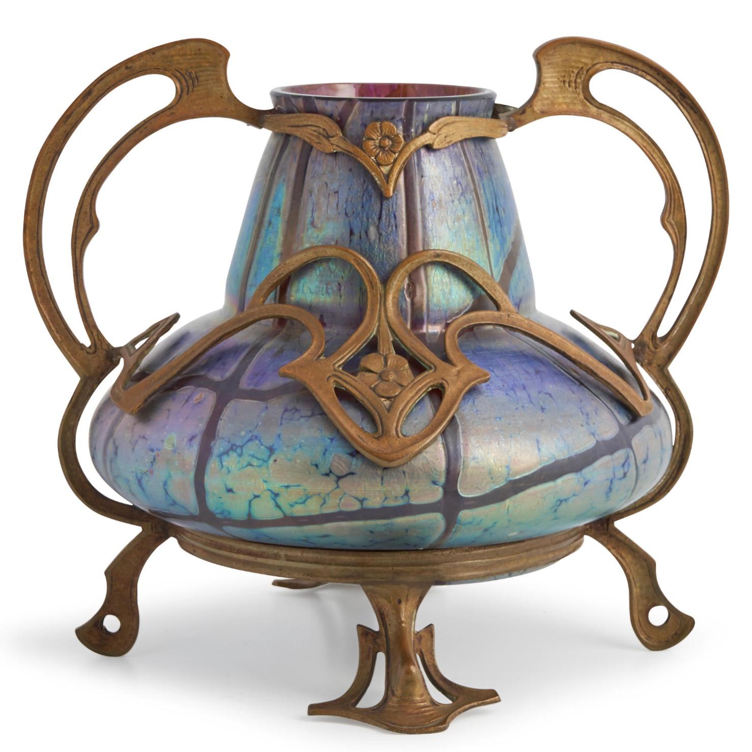 Vaso con montatura in vetro e metallo Loetz Pampas
Repubblica Ceca
Circa 1900
Non segnato 
Altezza: 7,5 pollici, da manico a manico 8,25 pollici

Condit: Molto buono, con un'usura commisurata all'età e all'uso, con qualche perdita nella