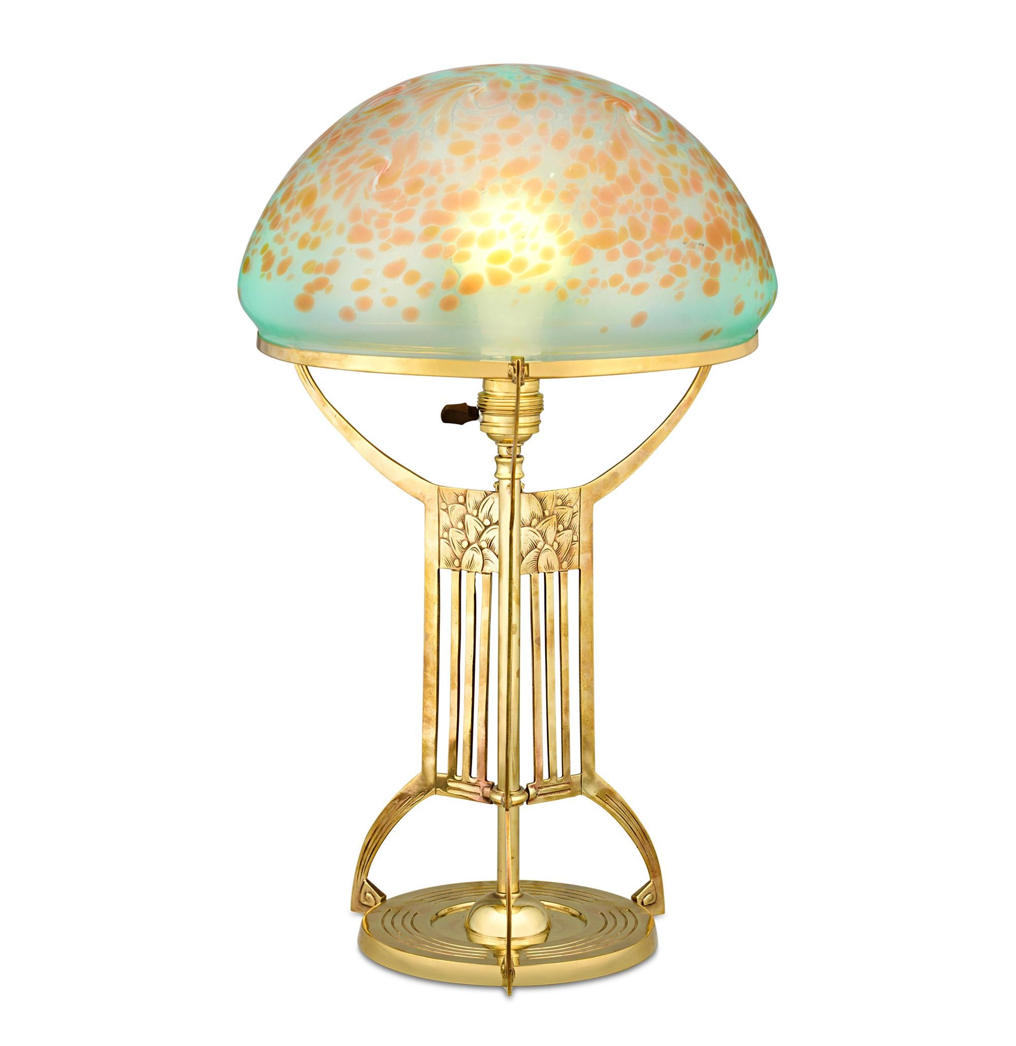 Table Lamp
Loetz
Circa 1905

An enchanting, colorful glow is emitted from this elegant Jugendstil table lamp by Loetz, which features the renowned Phaenomen Genre 2/207 glass shade, introduced in 1902. Crafted by Johann Loetz Witwe, the blown glass